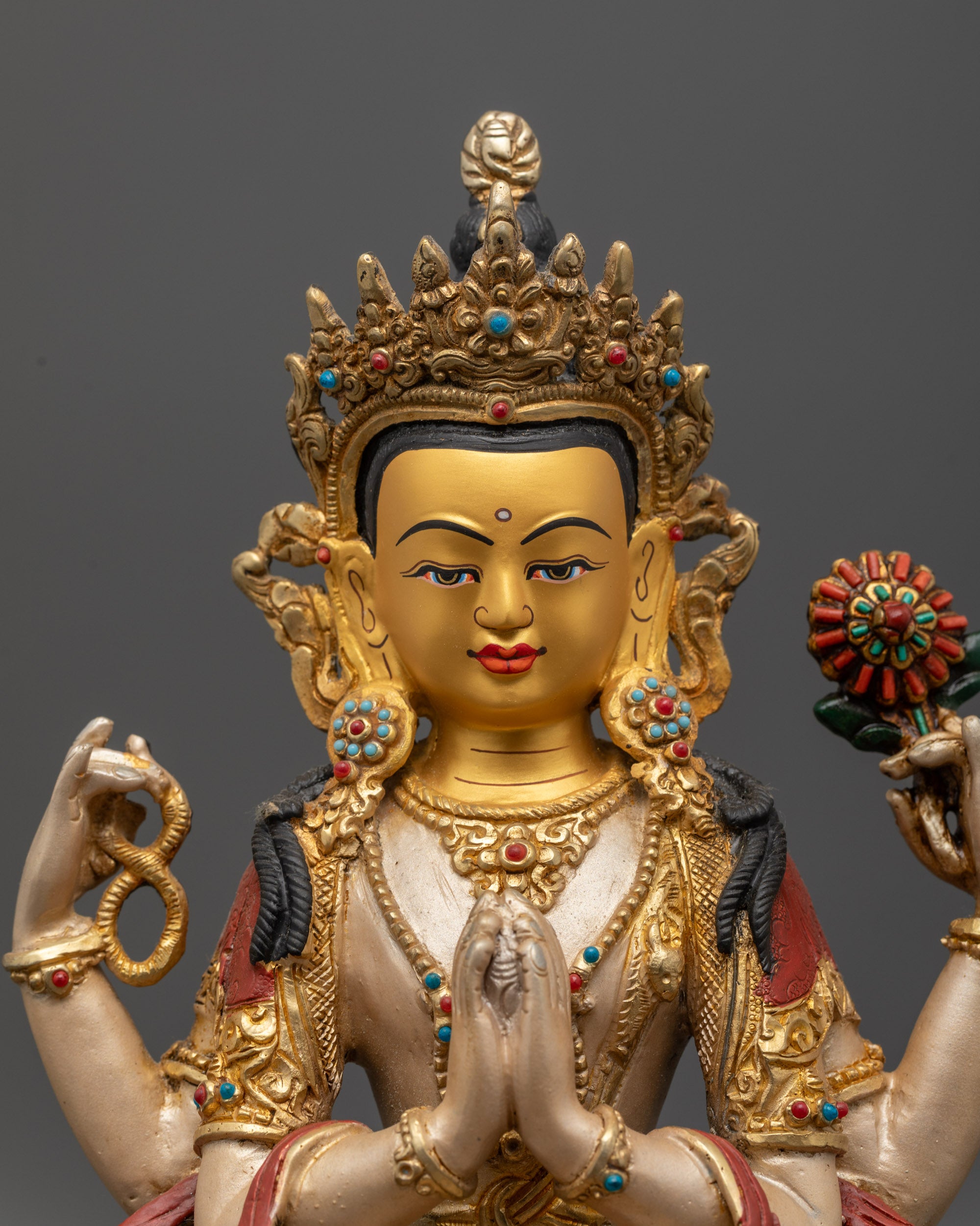 Close up Chenrezig statue highlighting gold-gilded face and intricate carvings
