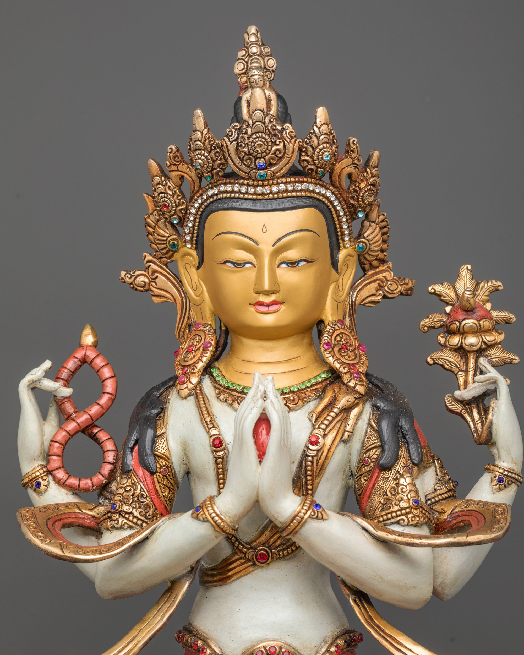 Close up Chenrezig statue showing crystal rosary and lotus held in four arms