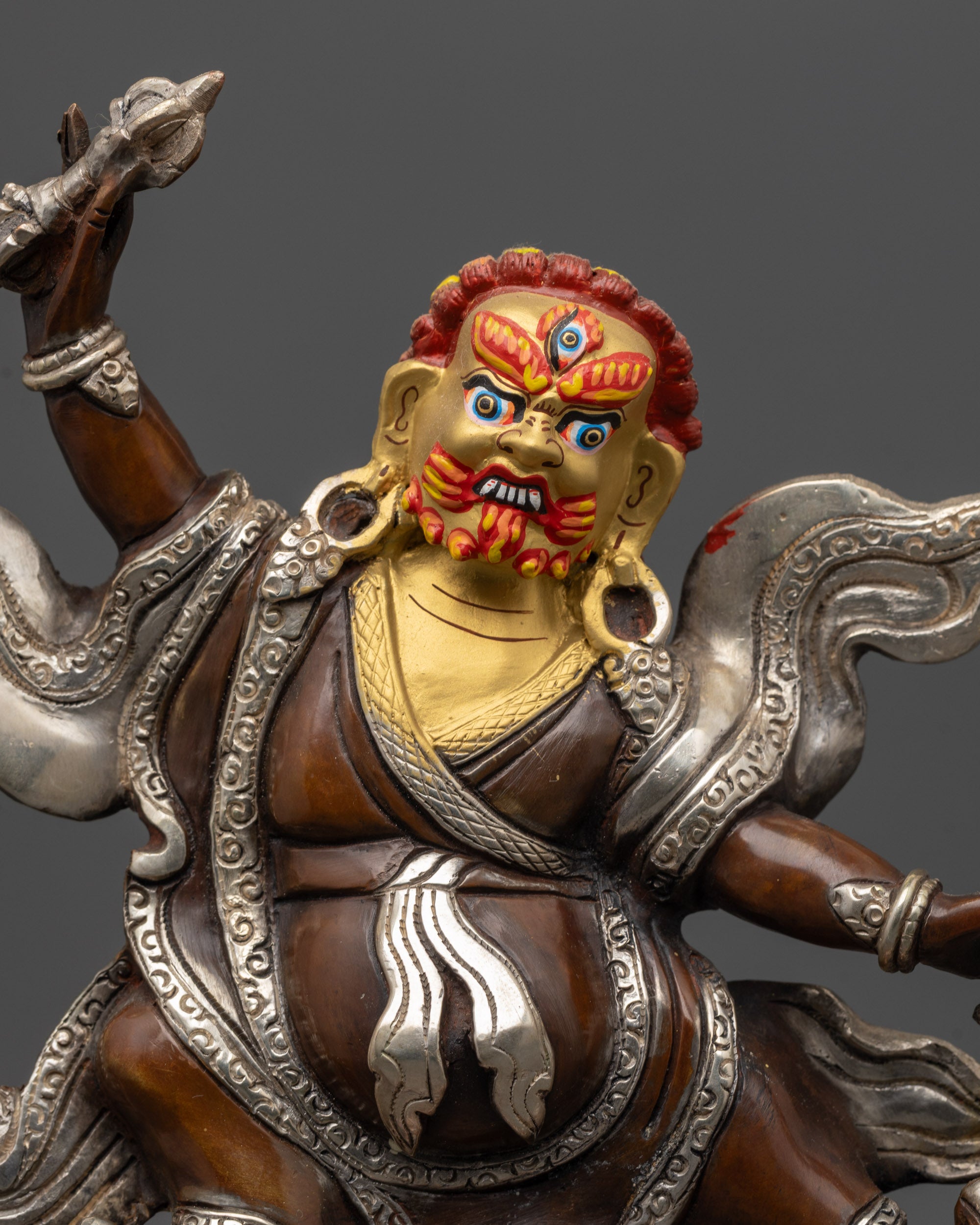 Close up Dorje Drolo statue showing wrathful face, third eye and silver-plated details
