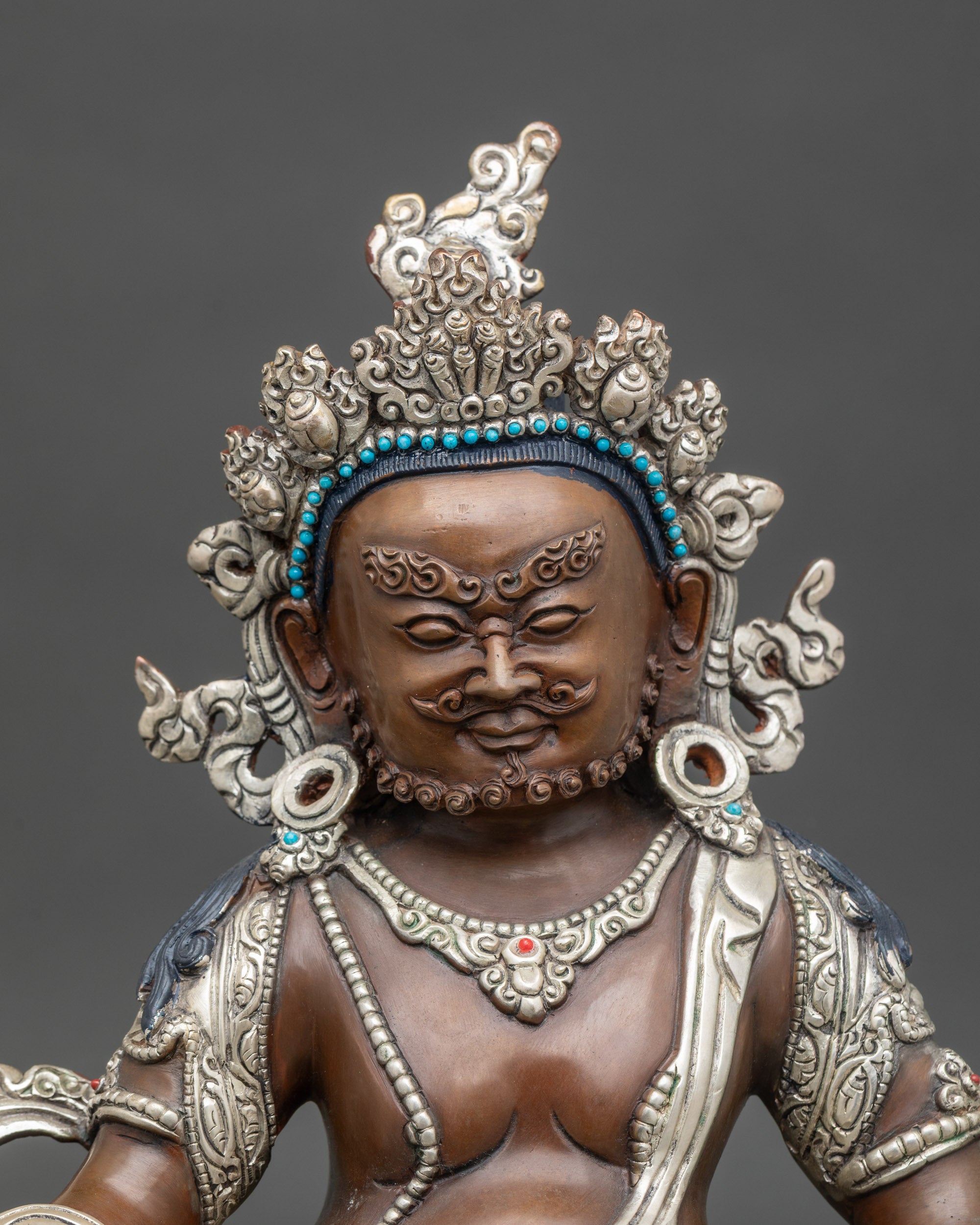 Close up Dzambhala wealth deity statue with semi-precious stones, oxidized silver-plated copper detail