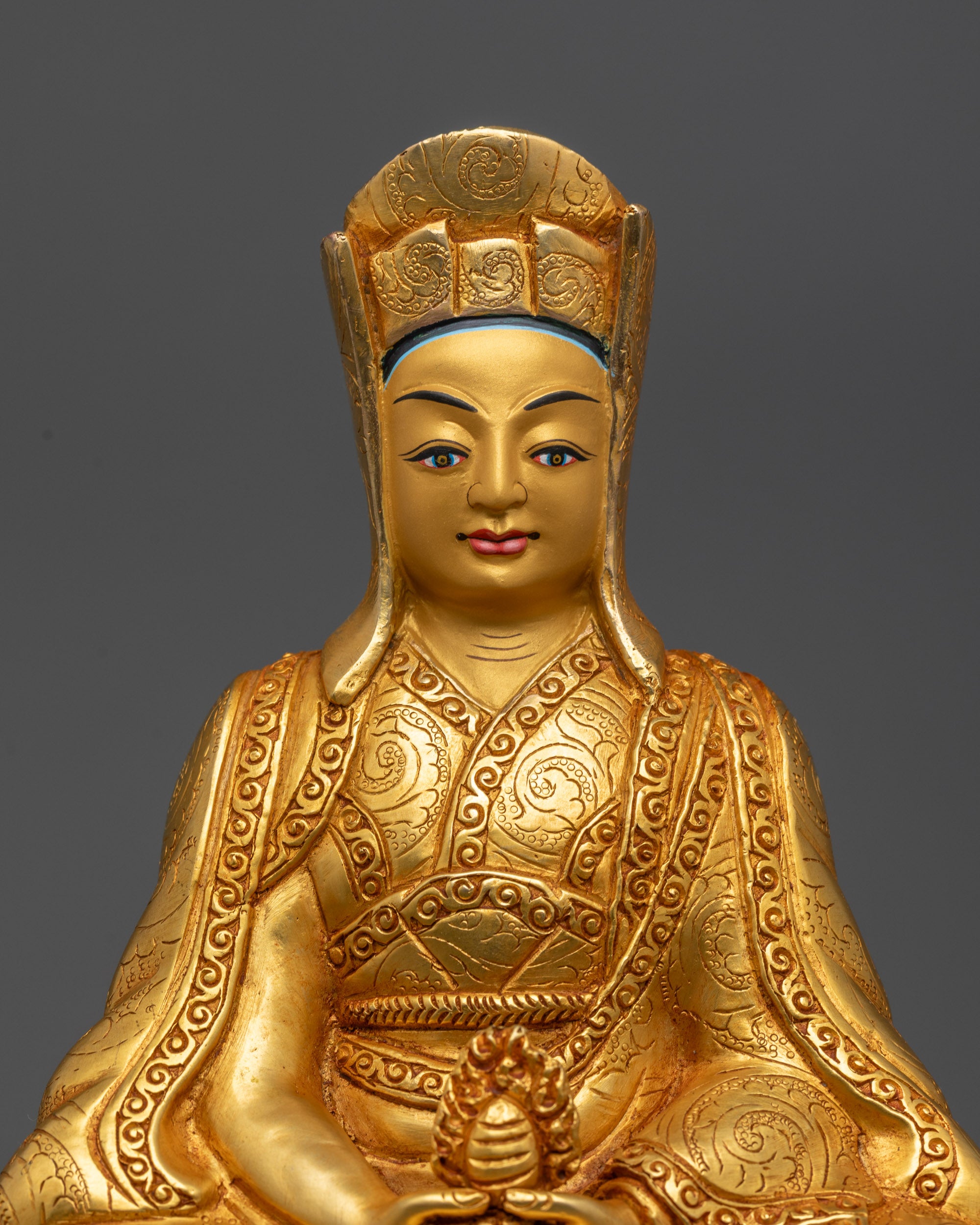 Close up Gampopa Statue showing gold gilded face and cintamani wish fulfilling jewel
