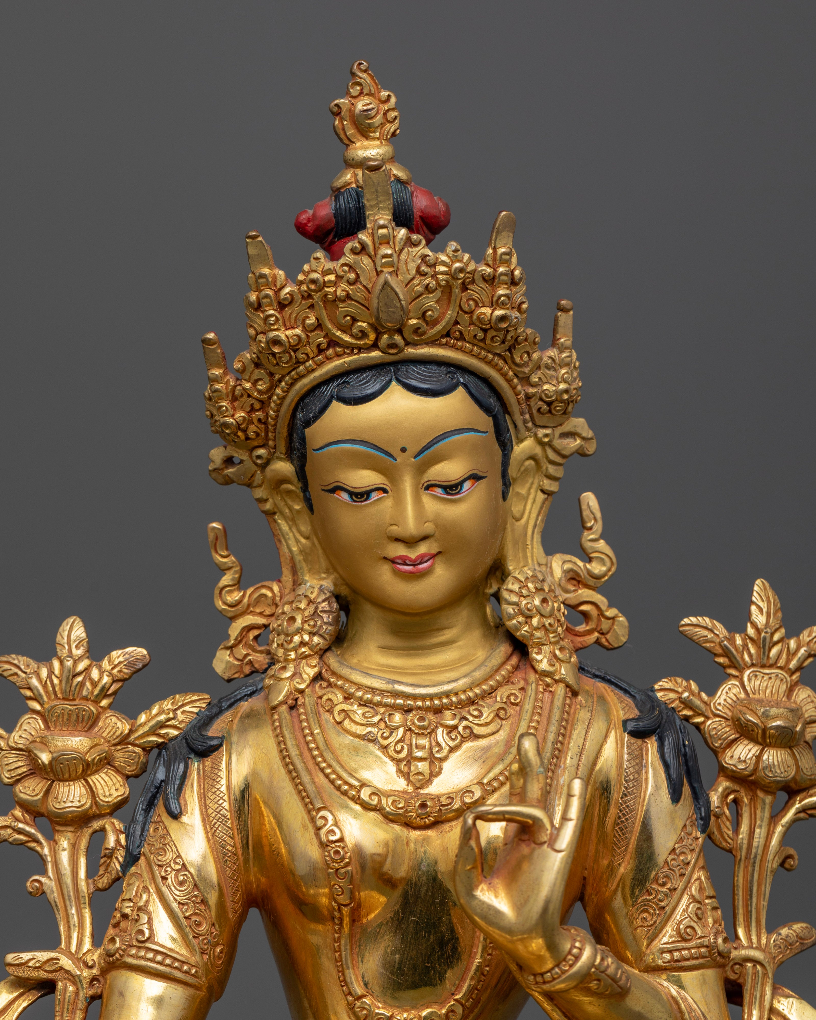 Close up Green Tara gold-painted face with five-jewelled crown and Utpala lotus stem, Himalayan Buddhist art