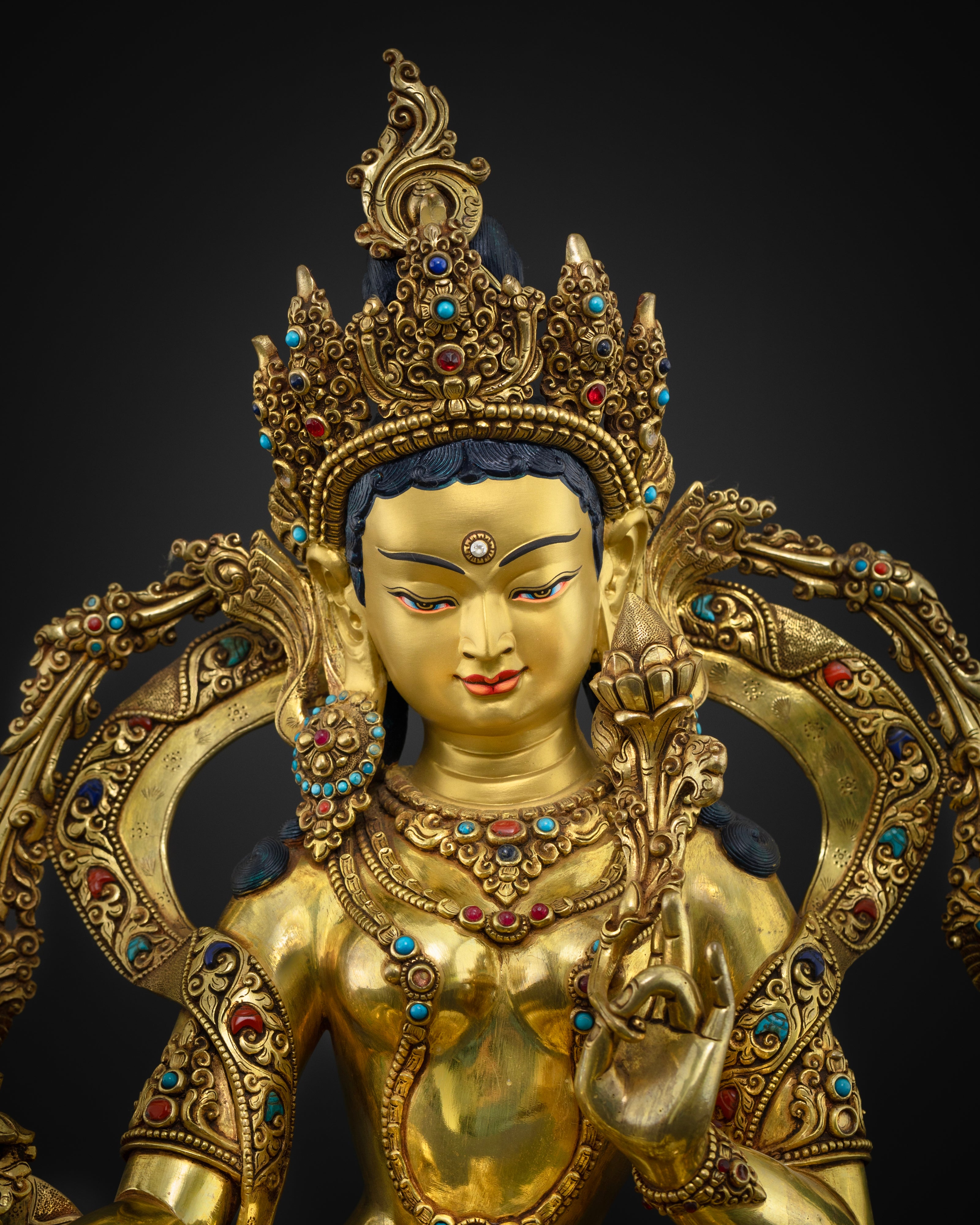 Close up Green Tara serene gold-gilded face with five-jeweled crown and semi-precious stones, handcrafted Nepalese sculpture