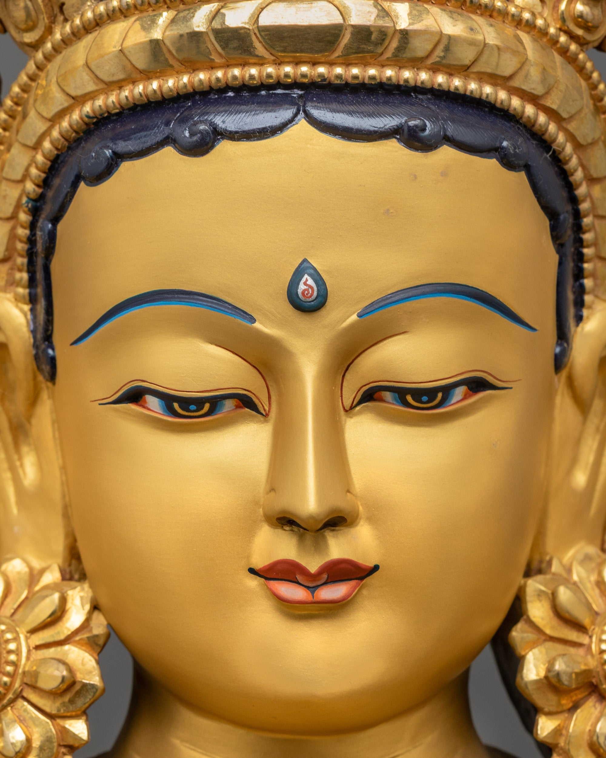 Close up Green Tara statue face with gold gilded details and serene tranquil expression