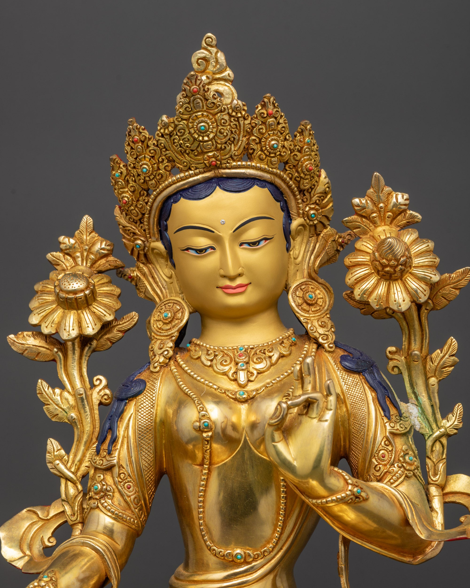 Close up Green Tara statue showing gold fire-gilded surface and floating robe
