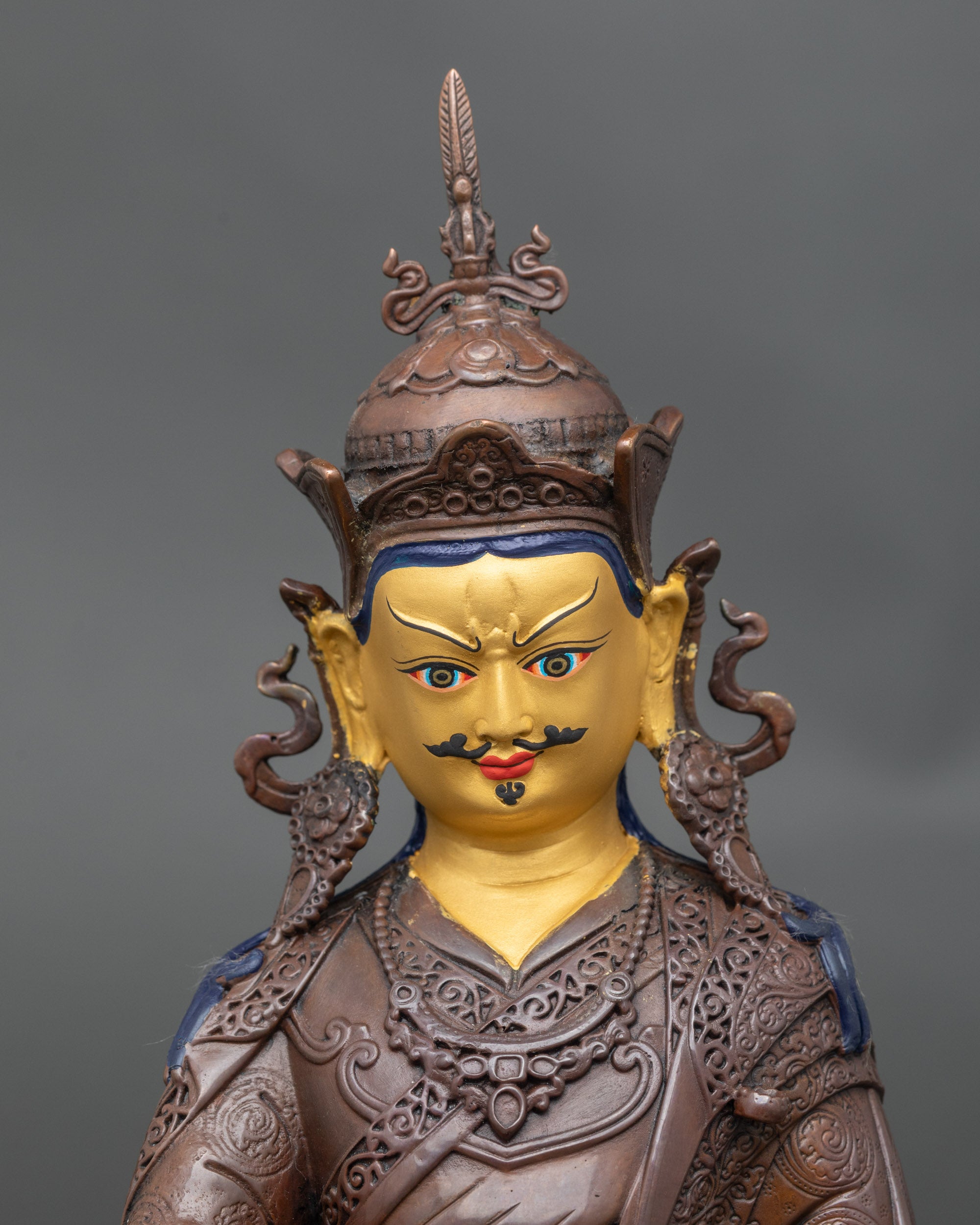 Close up Guru Padmasambhava face with serene expression and intricate robe carvings