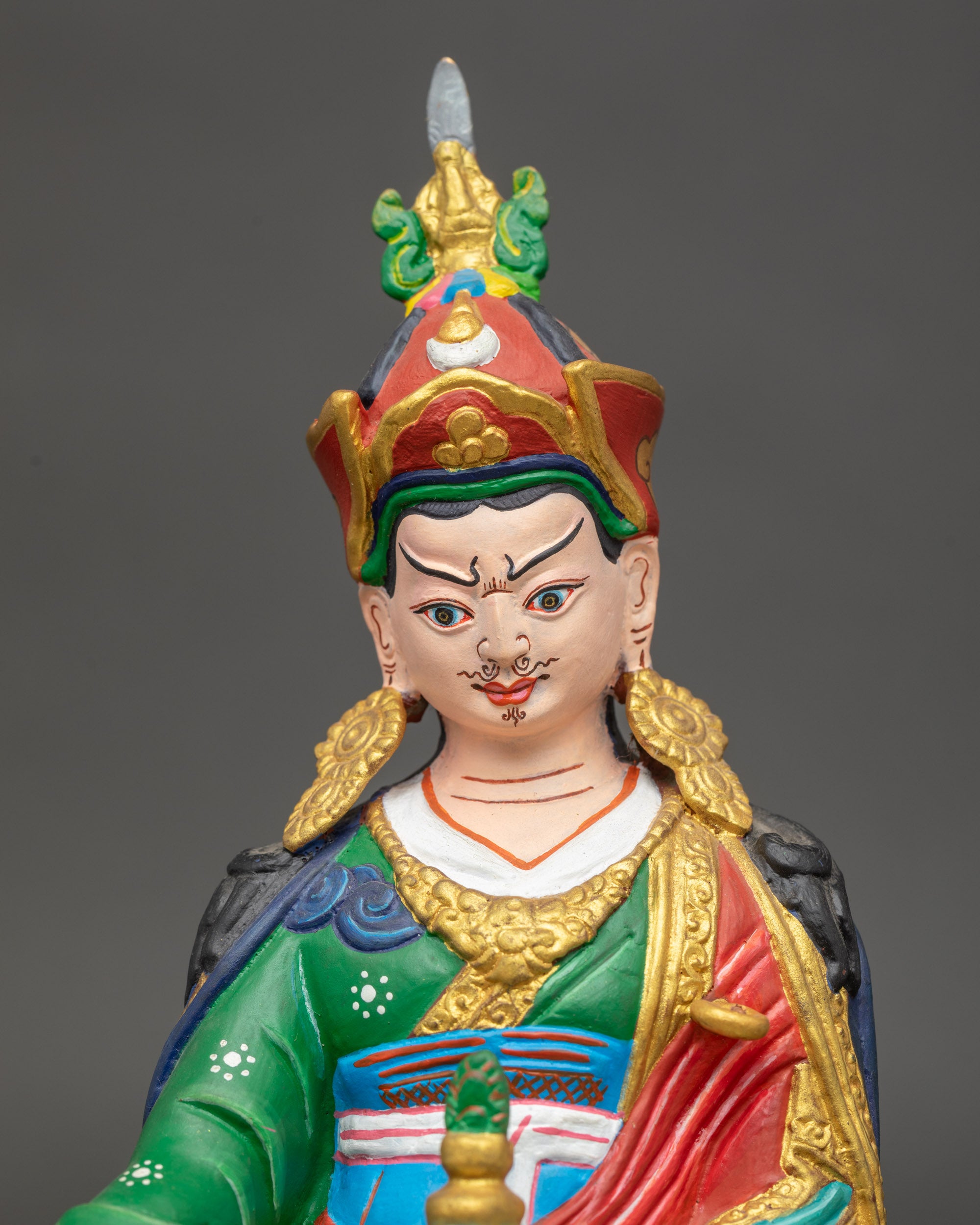 Close up Guru Rinpoche face with lotus hat, vibrant hand-painted Vajrayana statue