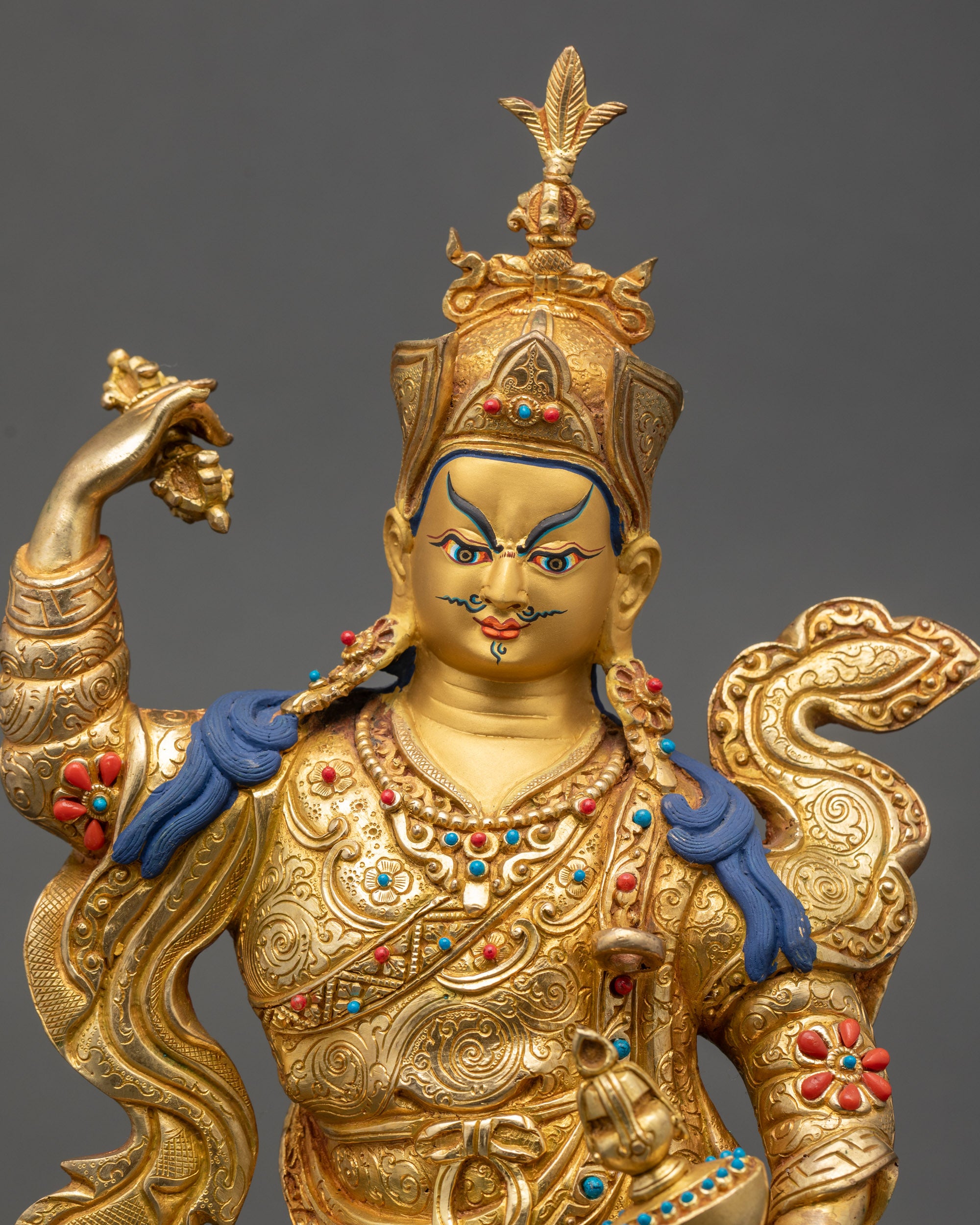 Close up Guru Rinpoche gold-painted face with flaming halo, semi-wrathful expression
