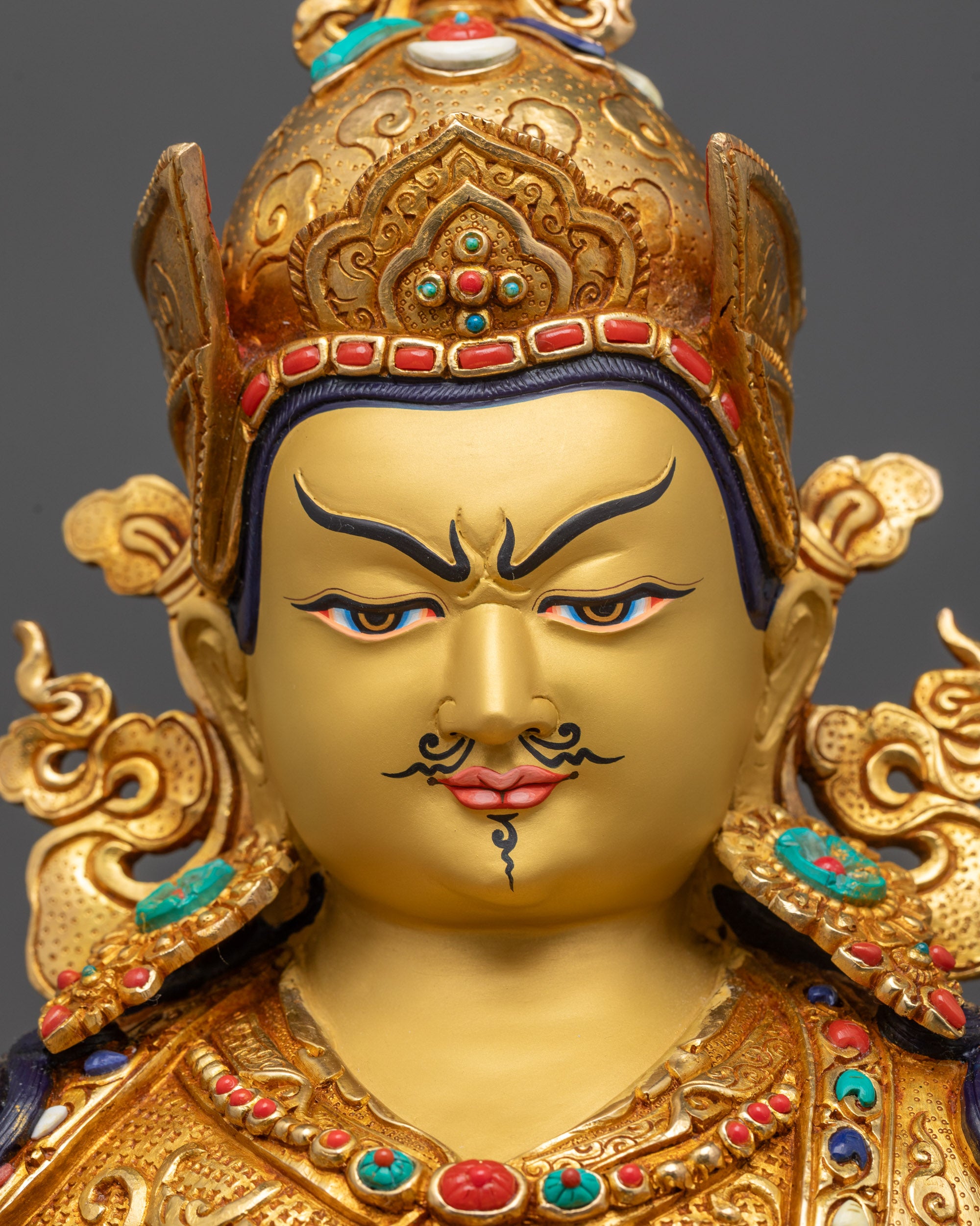 Close up Guru Rinpoche statue showing radiant gold-gilded face and intricate features