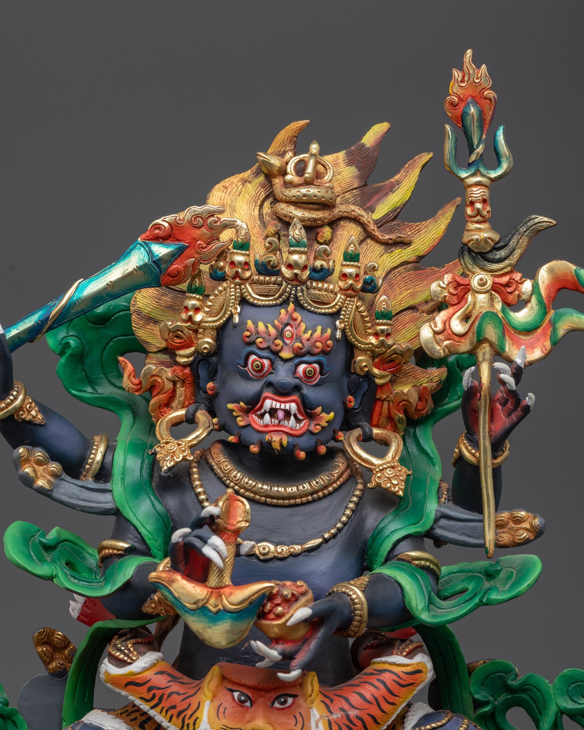 Close up Mahakala face showing blue body, third eye, and skull crown details