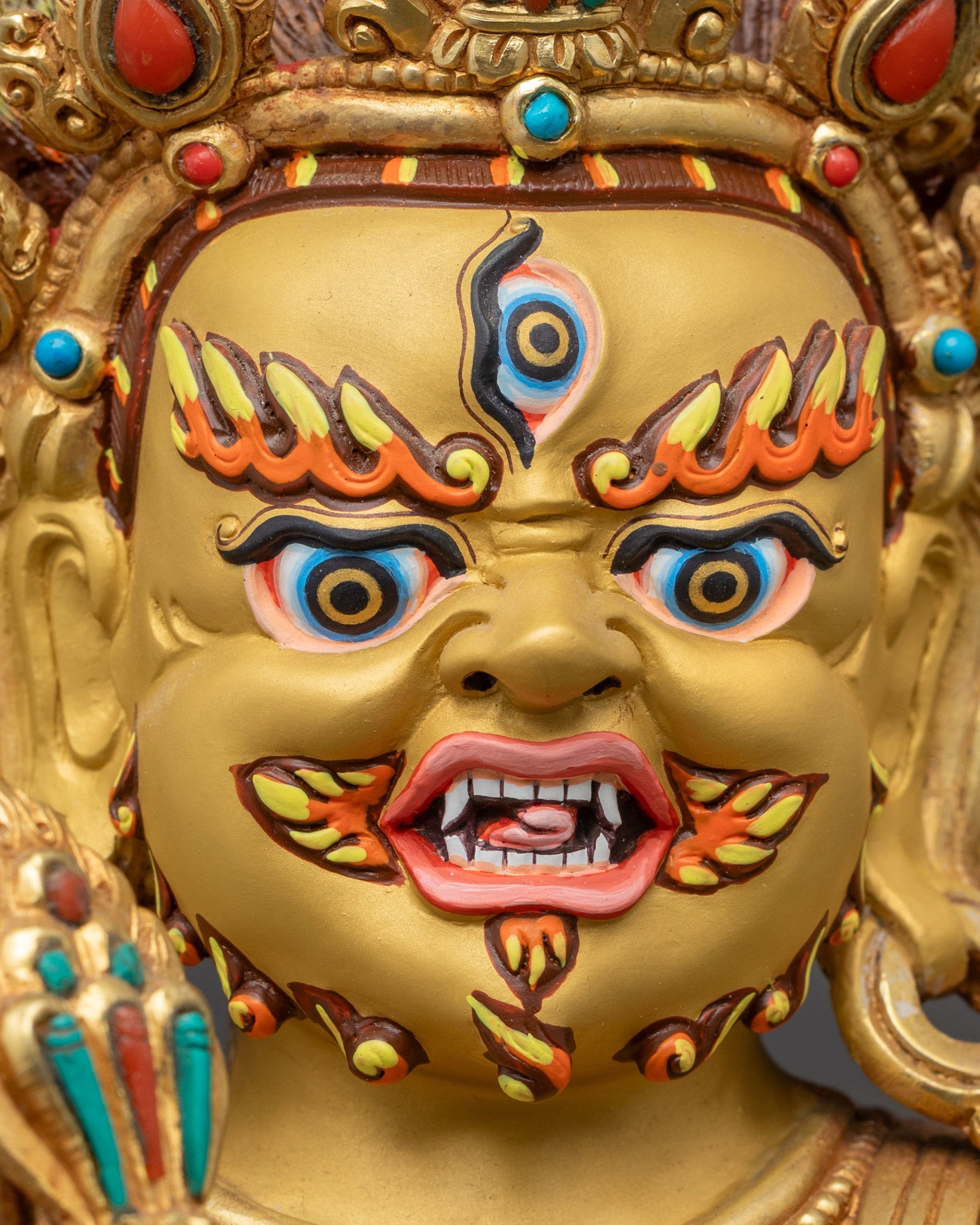 Close up Mahakala gold-gilded face with third eye and skull crown details