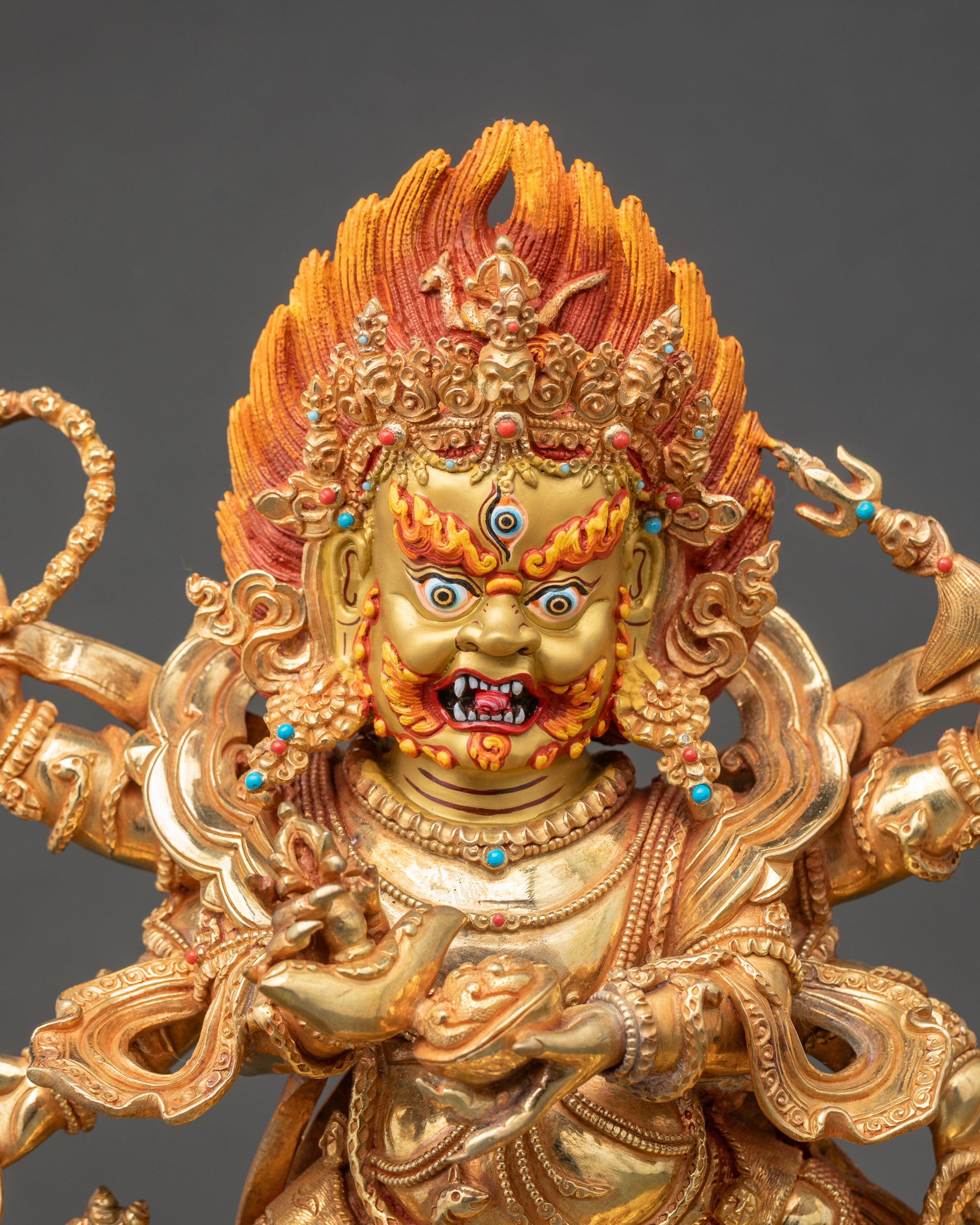 Close up Mahakala's face with a crown of skulls, wrathful expression, and gold-painted details