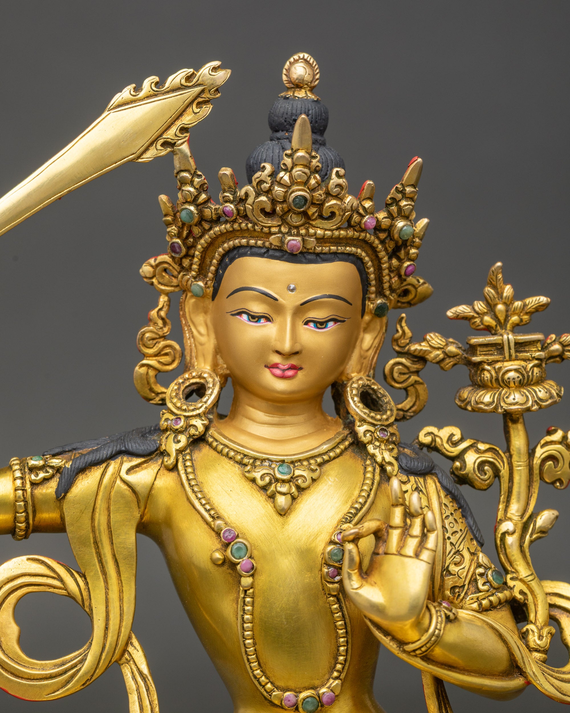 Close up Manjushri face serene expression with semi-precious stones and gold finish