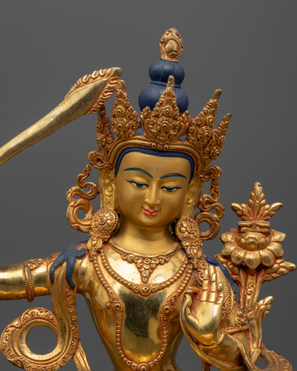 Close up Manjushri gold-painted face with wisdom sword and Utpala flower, hand-carved Newari Himalayan statue
