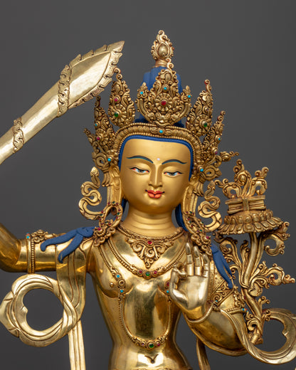 Close up Manjushri statue gold-painted face wisdom sword utpala flower Himalayan art