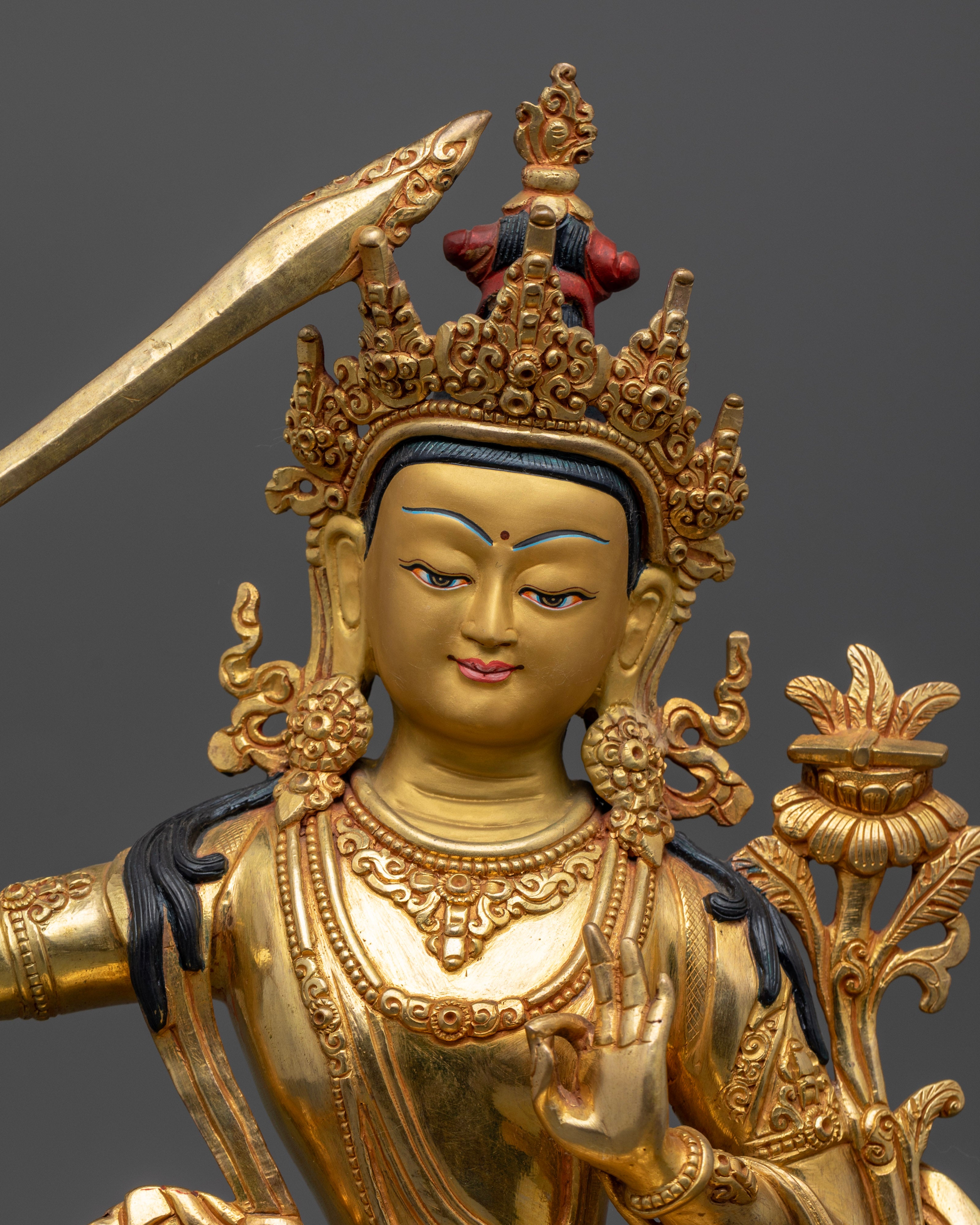 Close up Manjushri statue gold painted face Prajnaparamita lotus Himalayan art