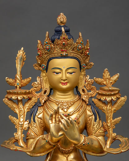 Close up Manjushri statue showing gold-painted face, semi-precious stones, and crown