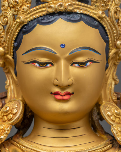 Close up Mother Tara Statue serene gold-gilded face with jeweled crown details
