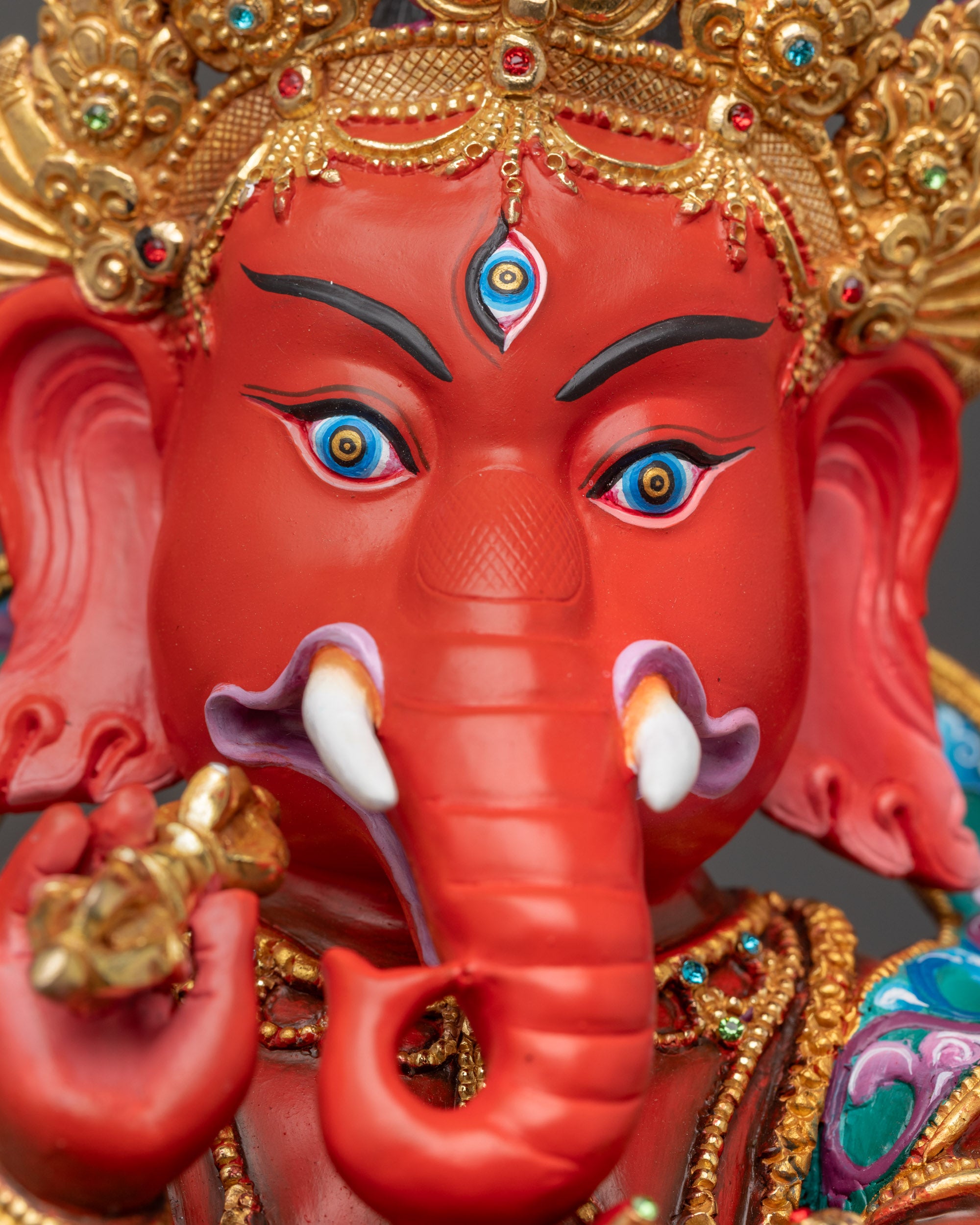 Close up Rakta Ganesh face with gold-plated crown, third eye, and fine detailing