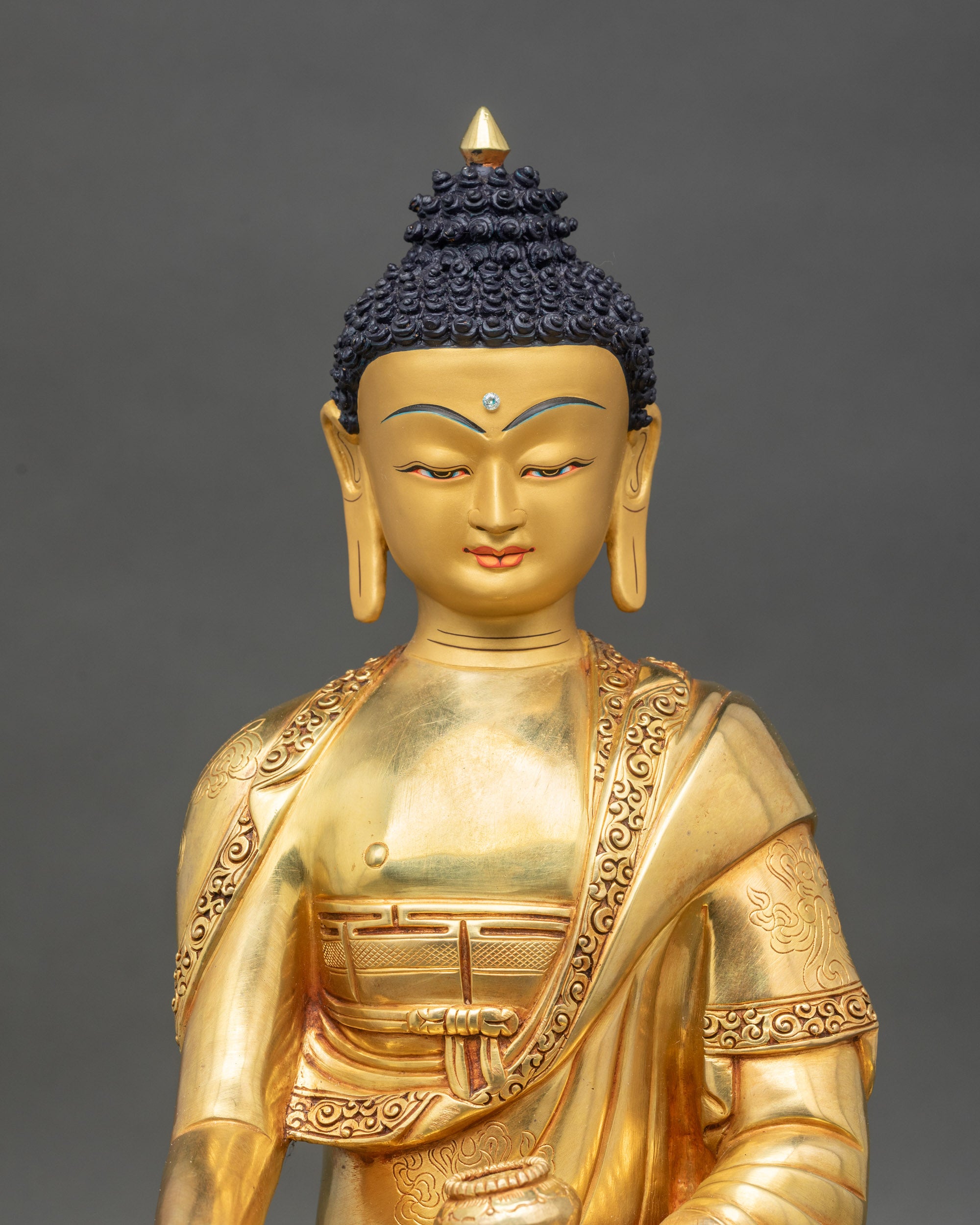 Close up Shakyamuni Buddha face gold painted copper Buddhist statue Patan Nepal artisan detail
