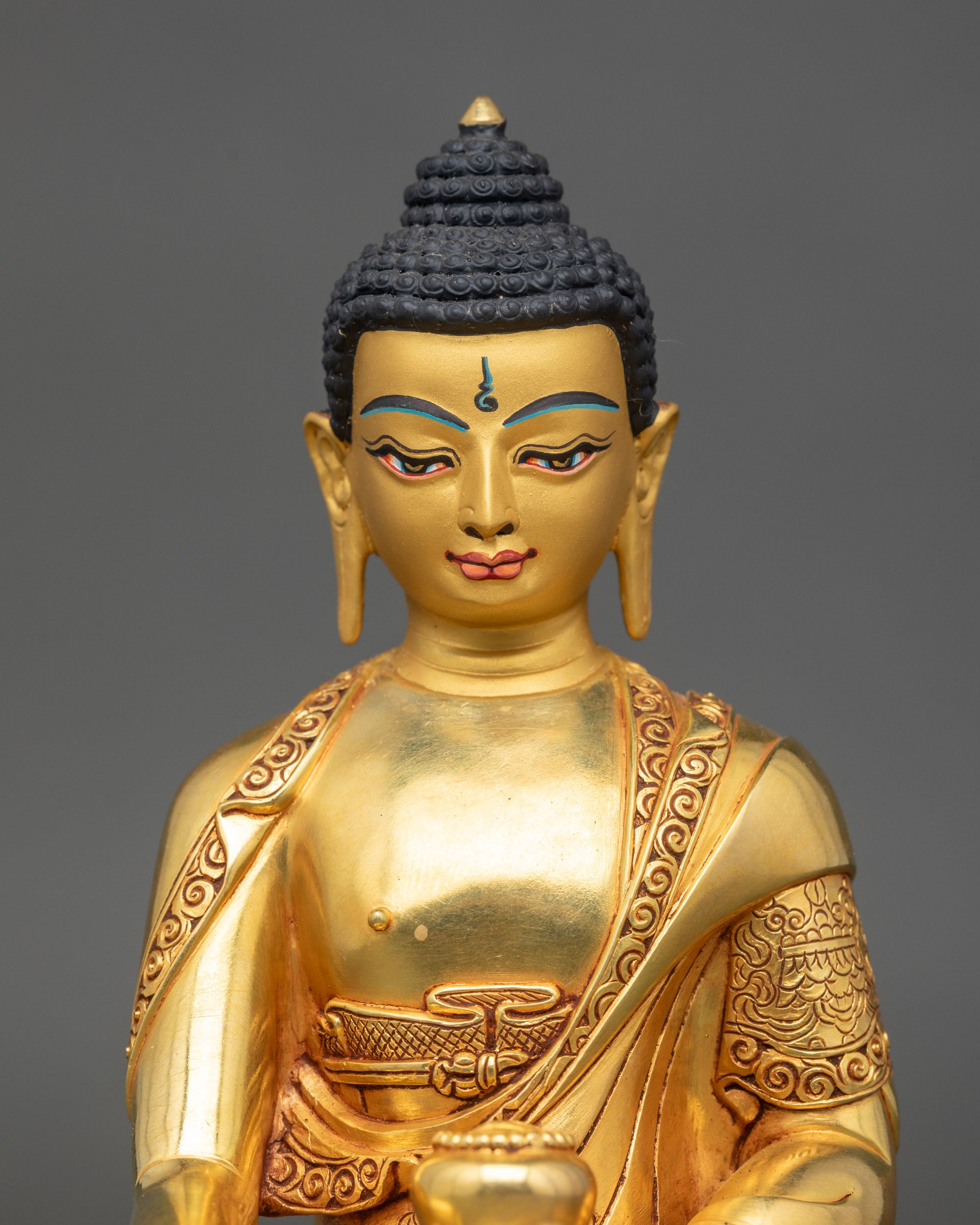 Close up Shakyamuni Buddha gold-painted face and detailed robe Patan Nepal sacred art