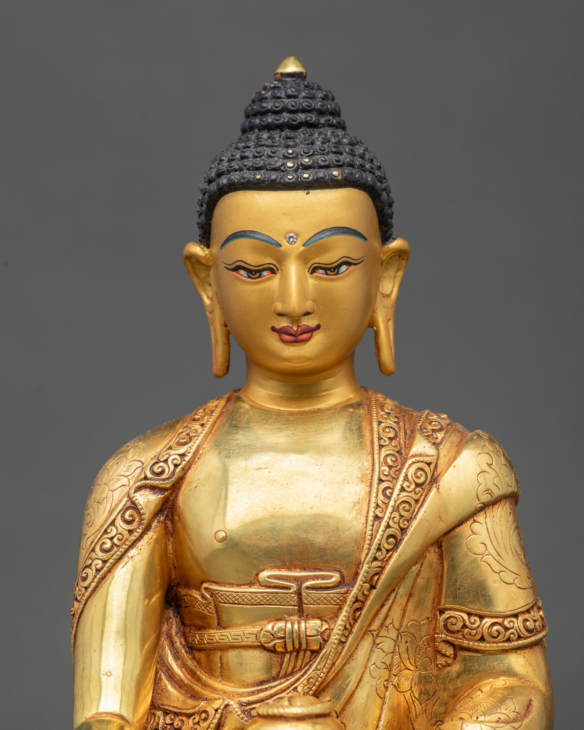 Close up Shakyamuni Buddha gold-painted face intricate robes meditative posture