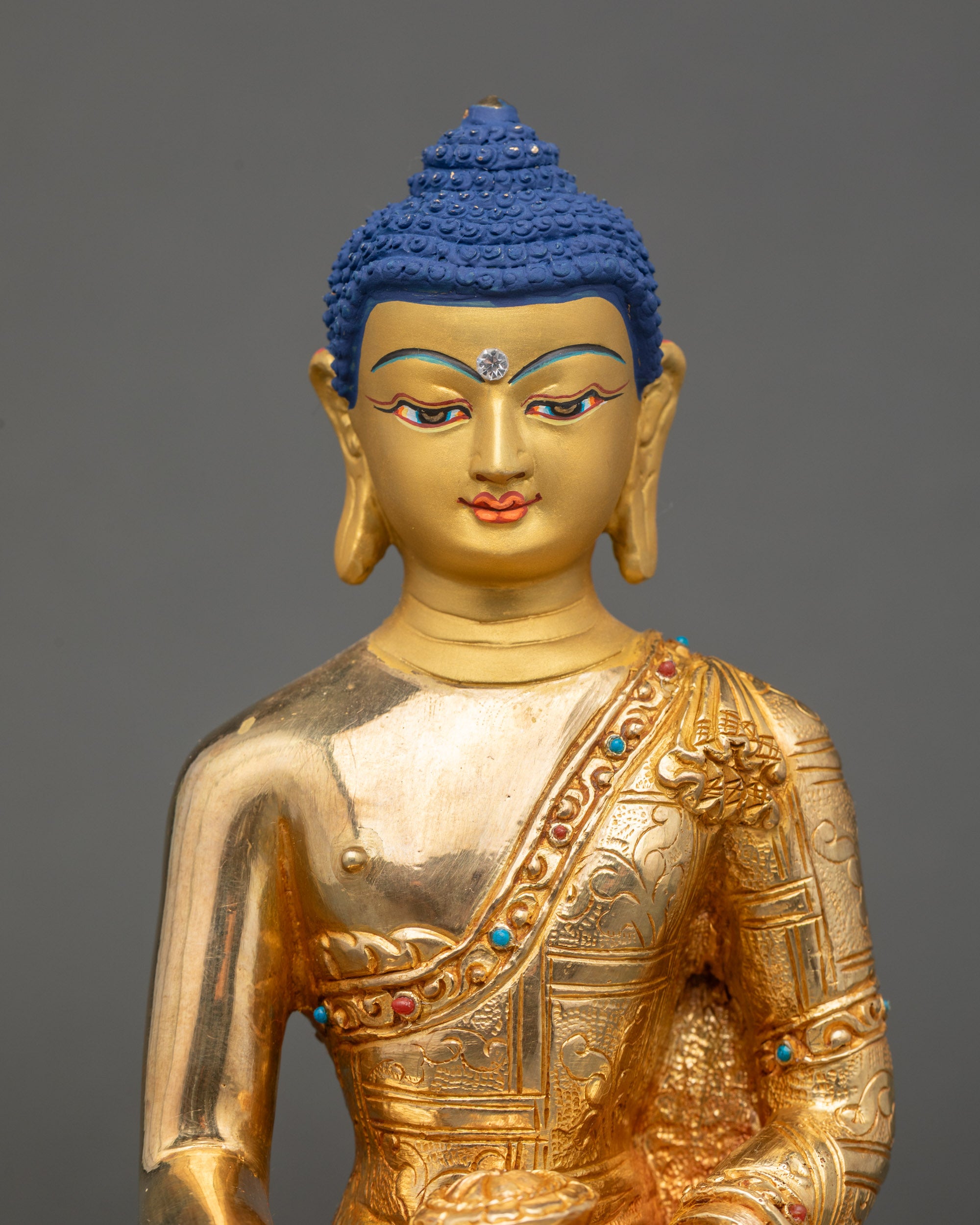 Close up Shakyamuni Buddha gold-painted face with semi-precious stone decoration