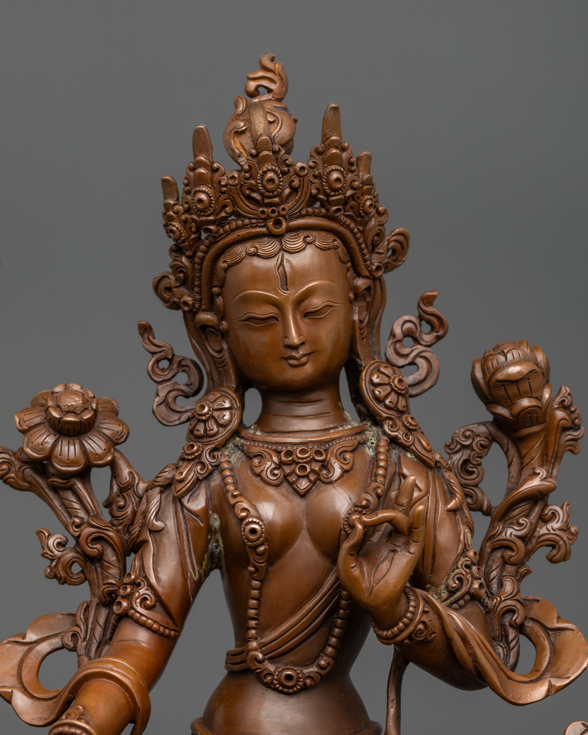 Close up Sita Tara Statue face with five jeweled crown and intricate robe carvings
