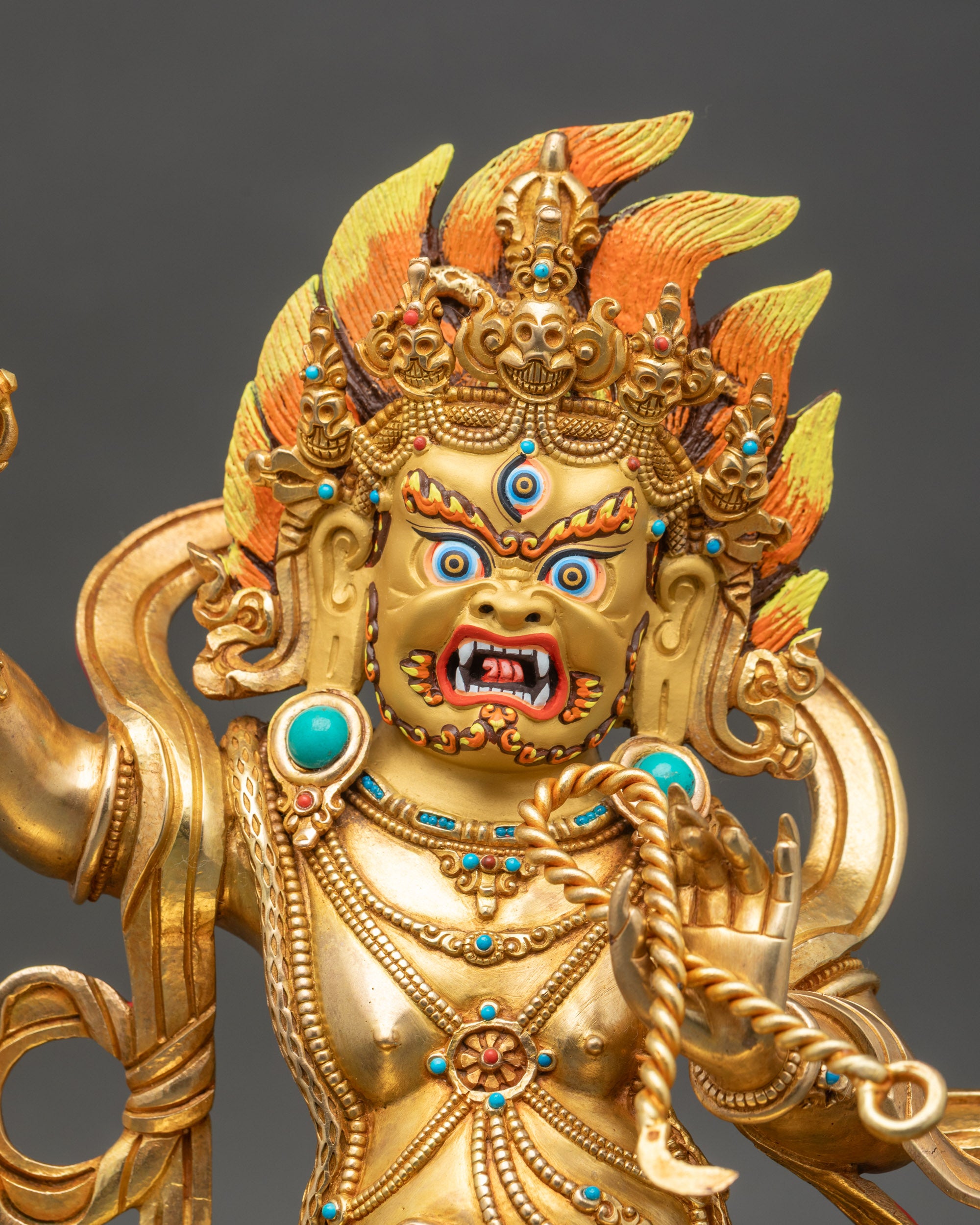 Close up Vajrapani statue showing gold-painted face, vajra, lasso