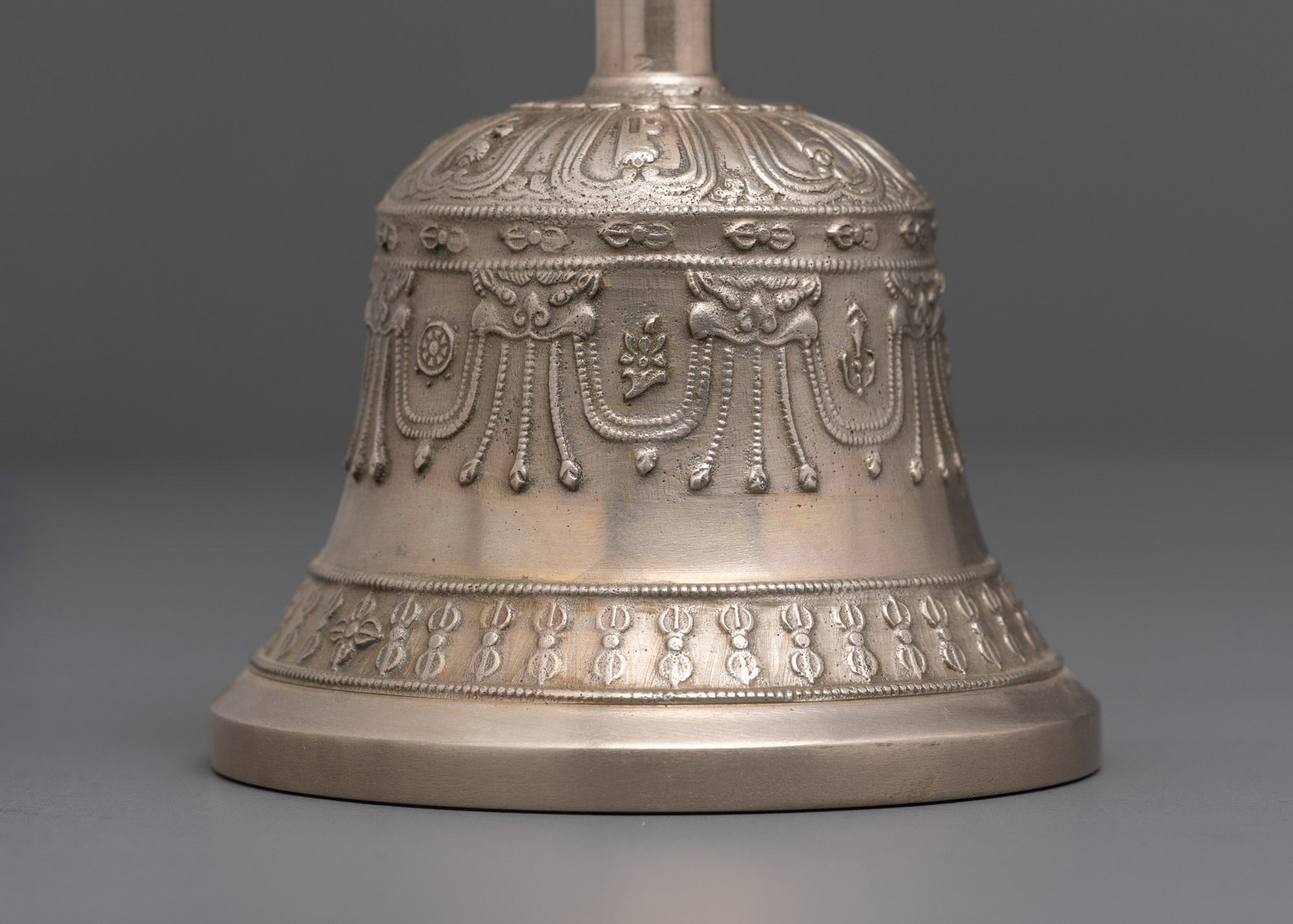 Close up angled view of bronze bell with handle and hand-carved sacred deity