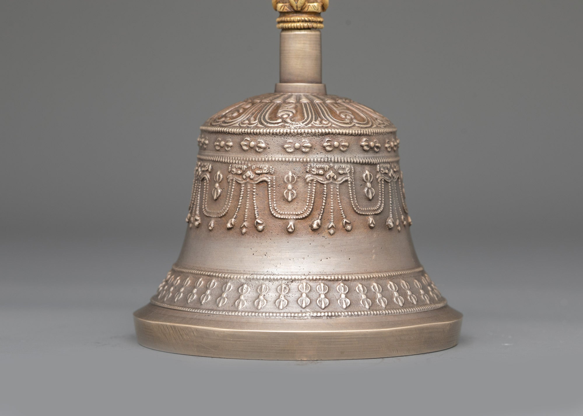 Close up bronze bell with carved copper deity handle for meditation and puja