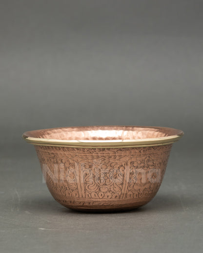 Close up copper water offering bowl with floral vine motifs Newari craftsmanship