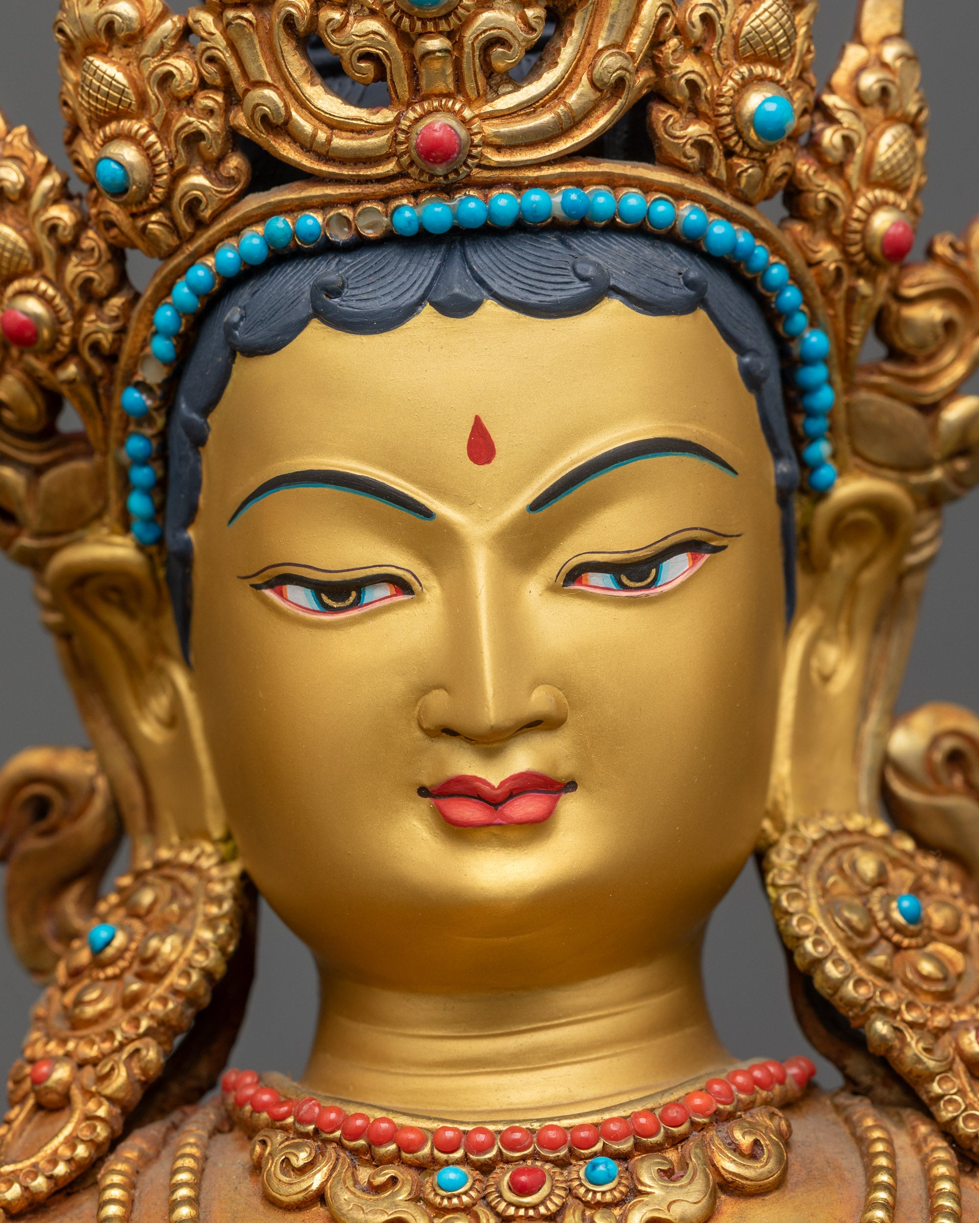 Close up face of Green Tara Statue showing serene expression and gold-gilded face
