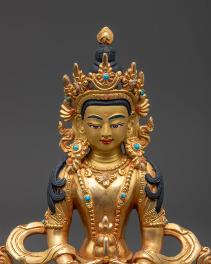Close up gold-gilded face of Amitayus statue with tranquil expression and fire-gilded details
