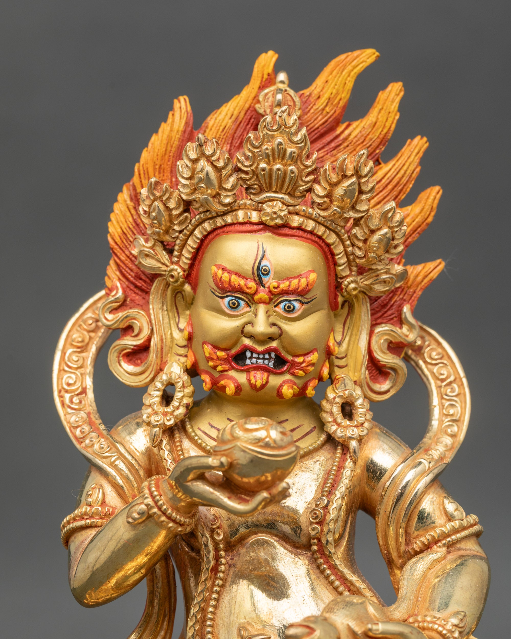 Close up gold-painted face Black Dzambhala wrathful guardian of abundance