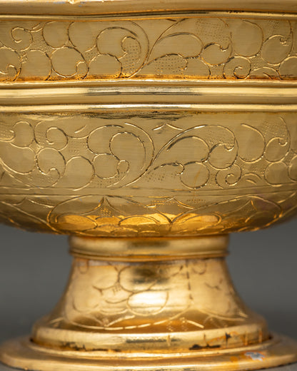 Close up gold and silver-plated water offering bowl with intricate floral motifs