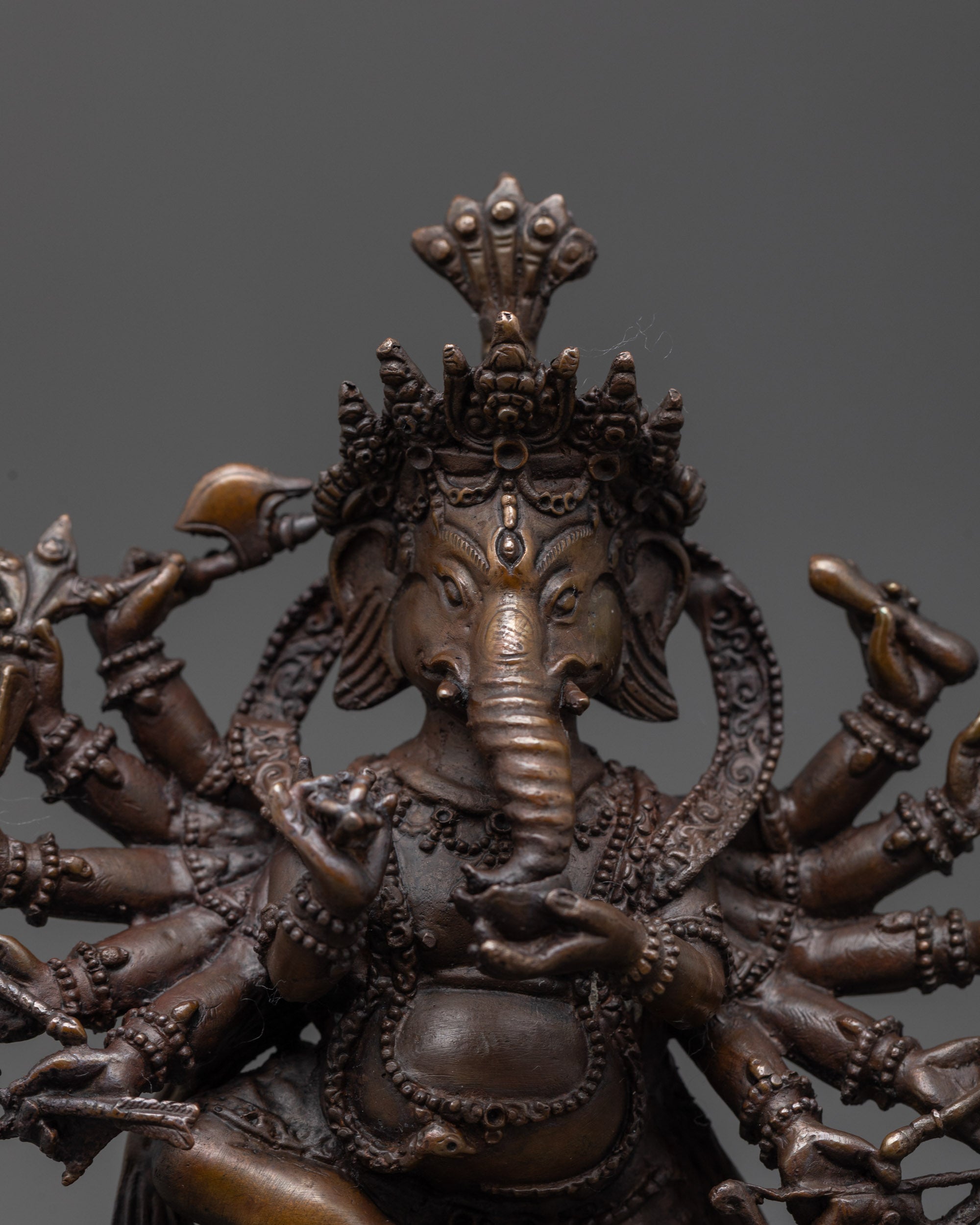 Close up of 12 Armed Ganesha showing five-jeweled crown and sacred objects in hands