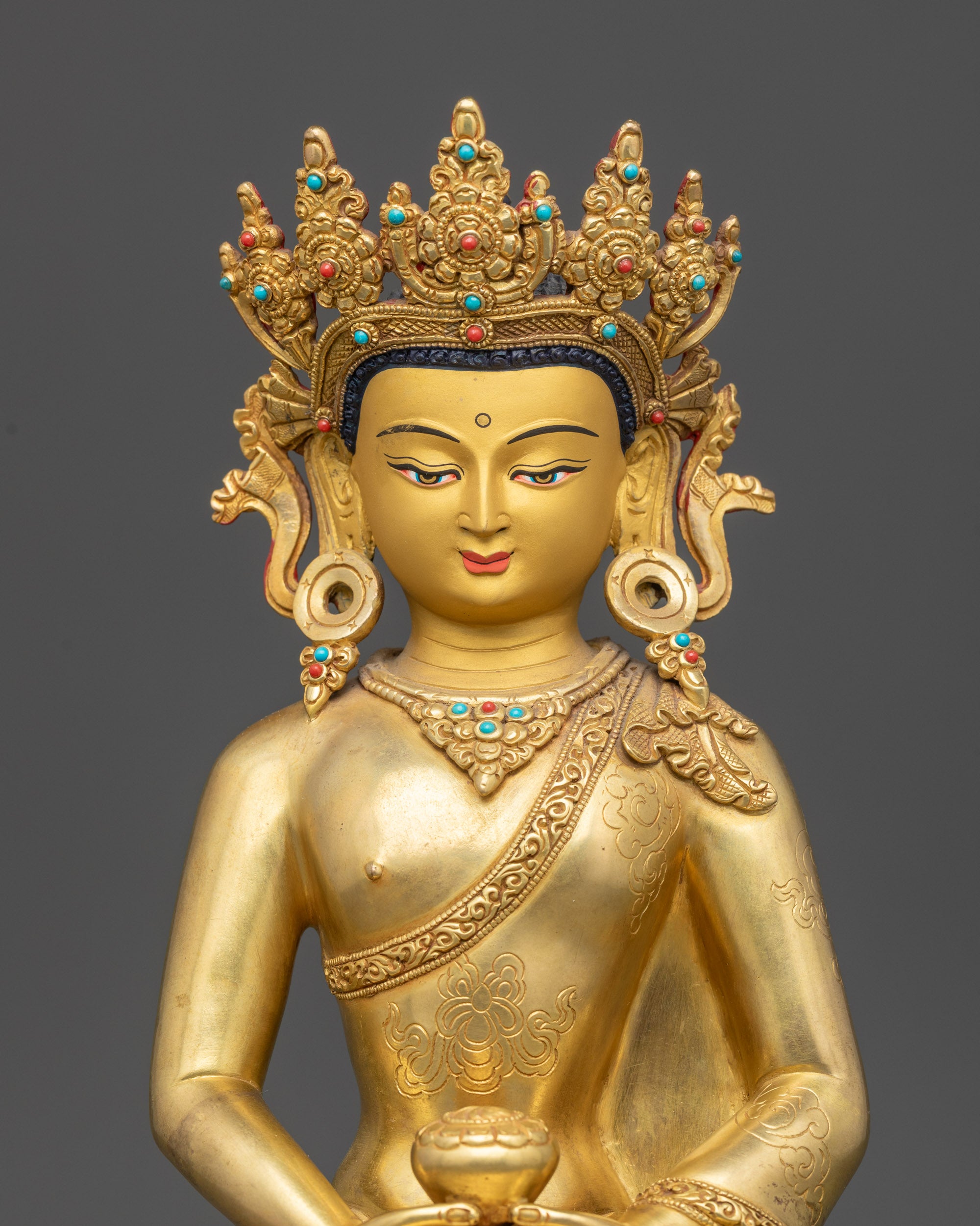 Close up of Amitabha Buddha crown and intricate robe carvings on gold-gilded face
