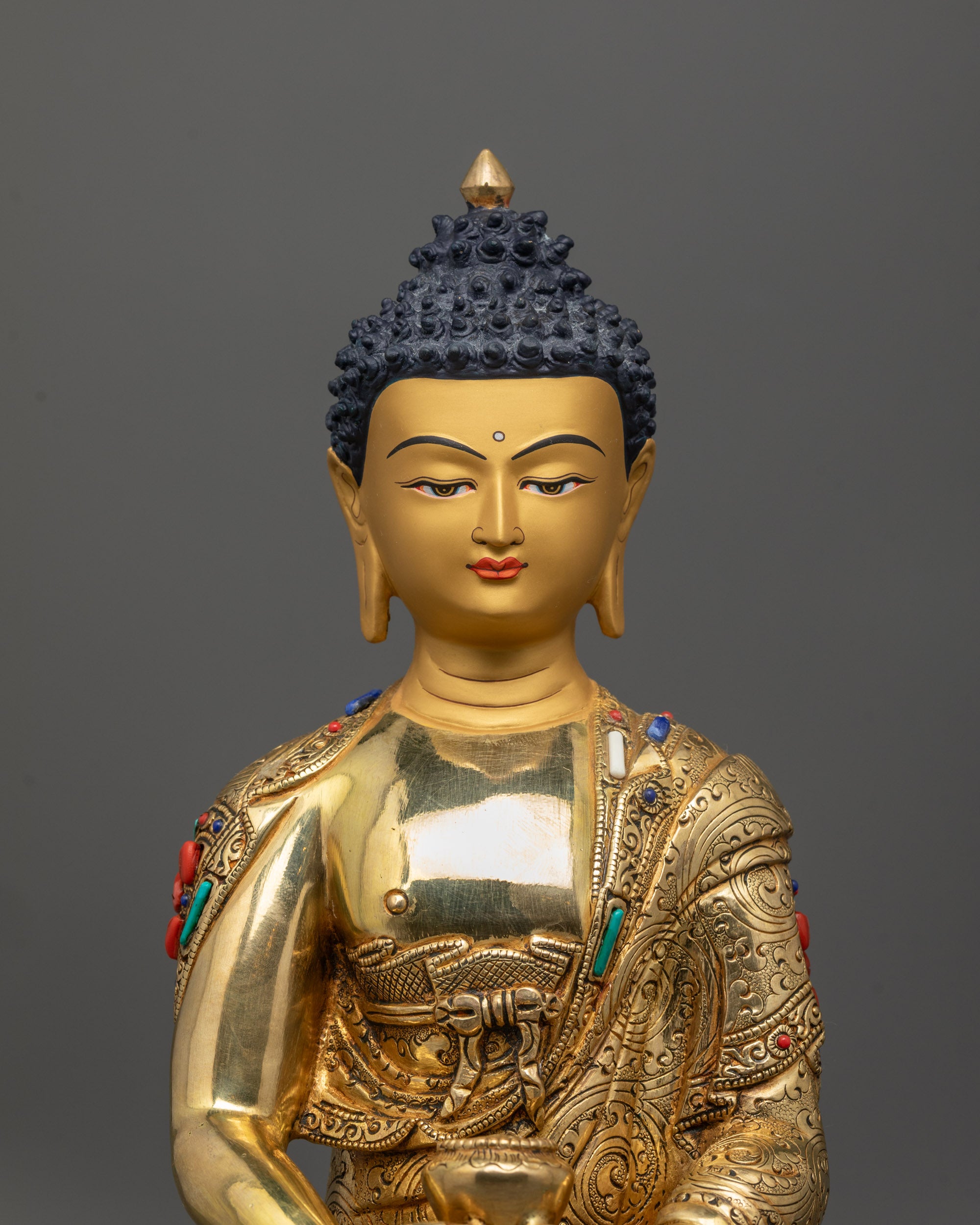 Close up of Amitabha Buddha statue showing polished carved garment and intricate patterns
