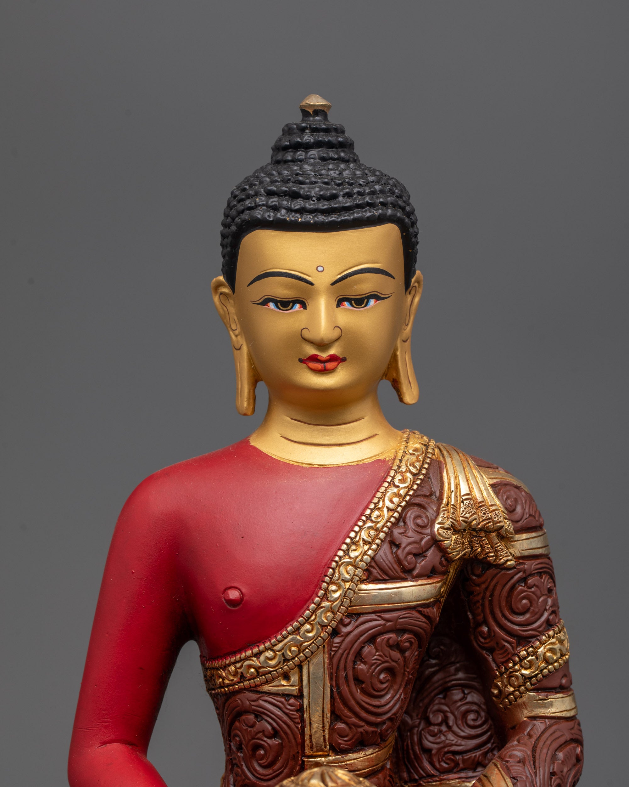 Close up of Amitabha Buddha statue showing red-painted body and gold-gilded face