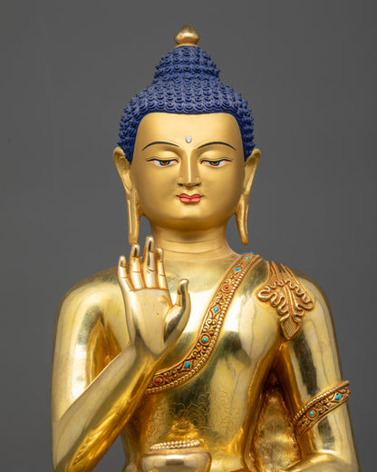 Close up of Amoghasiddhi Buddha statue showing serene gold-gilded face and polished finish