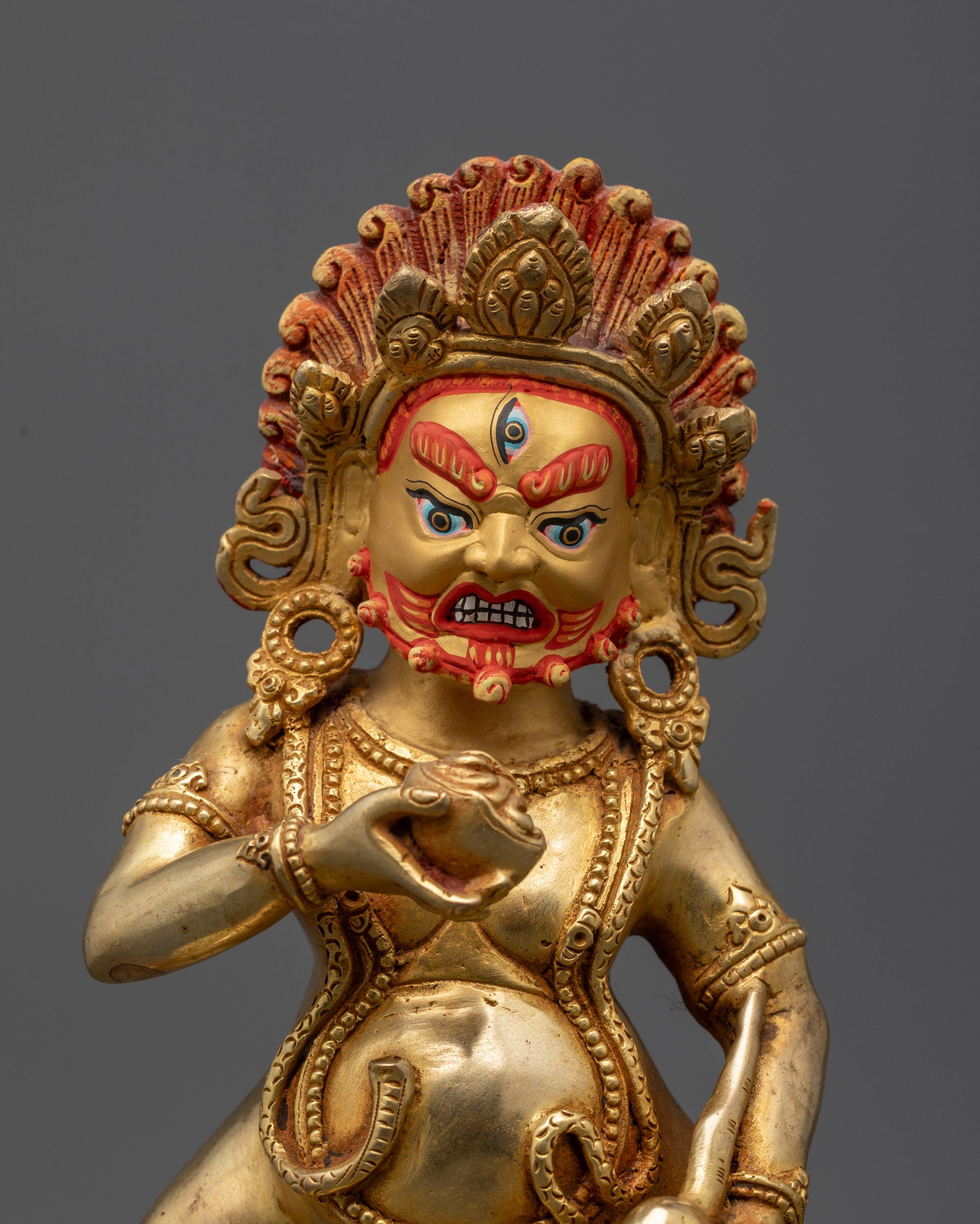 Close up of Black Jambhala face with third eye, serpent ornaments, and mongoose