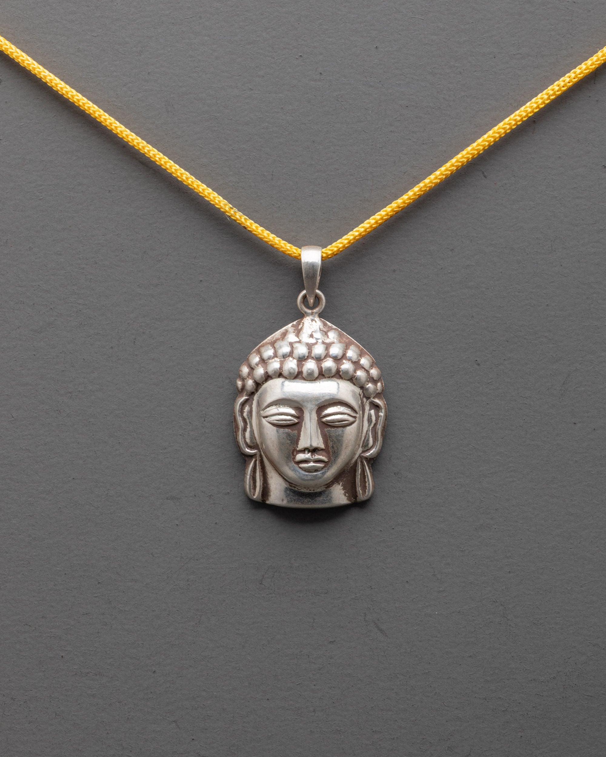 Close up of Buddha Head Locket from Patan, Nepal, highlighting detailed silver craftsmanship