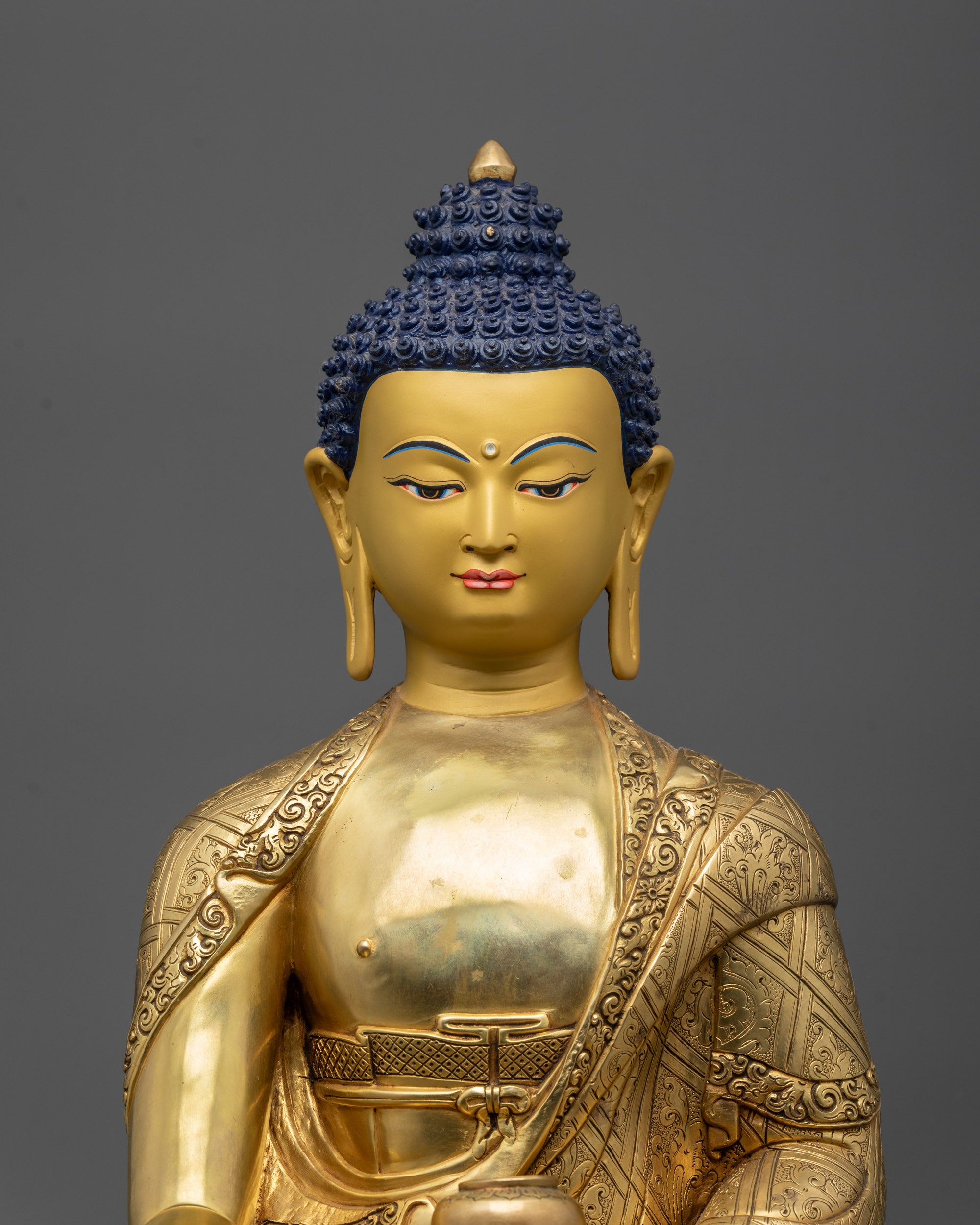 Close up of Buddha Shakyamuni statue showing gold-gilded face and intricate robe details