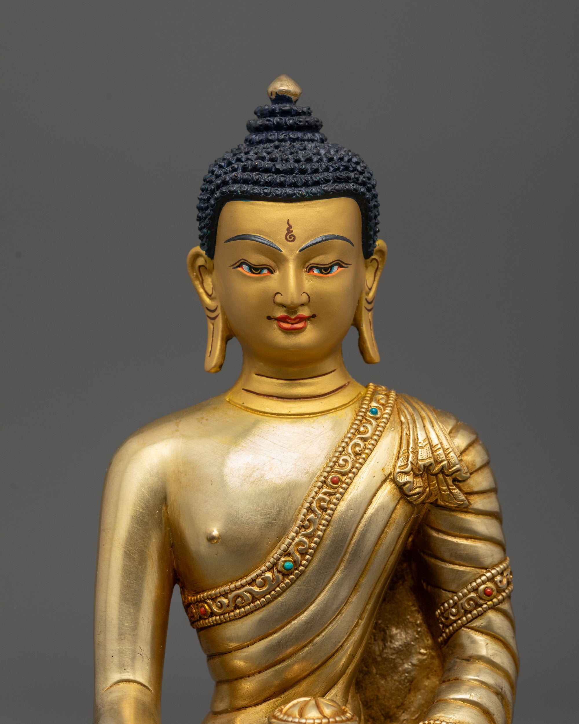 Close up of Buddha’s calm face and polished robe adorned with semi-precious stones
