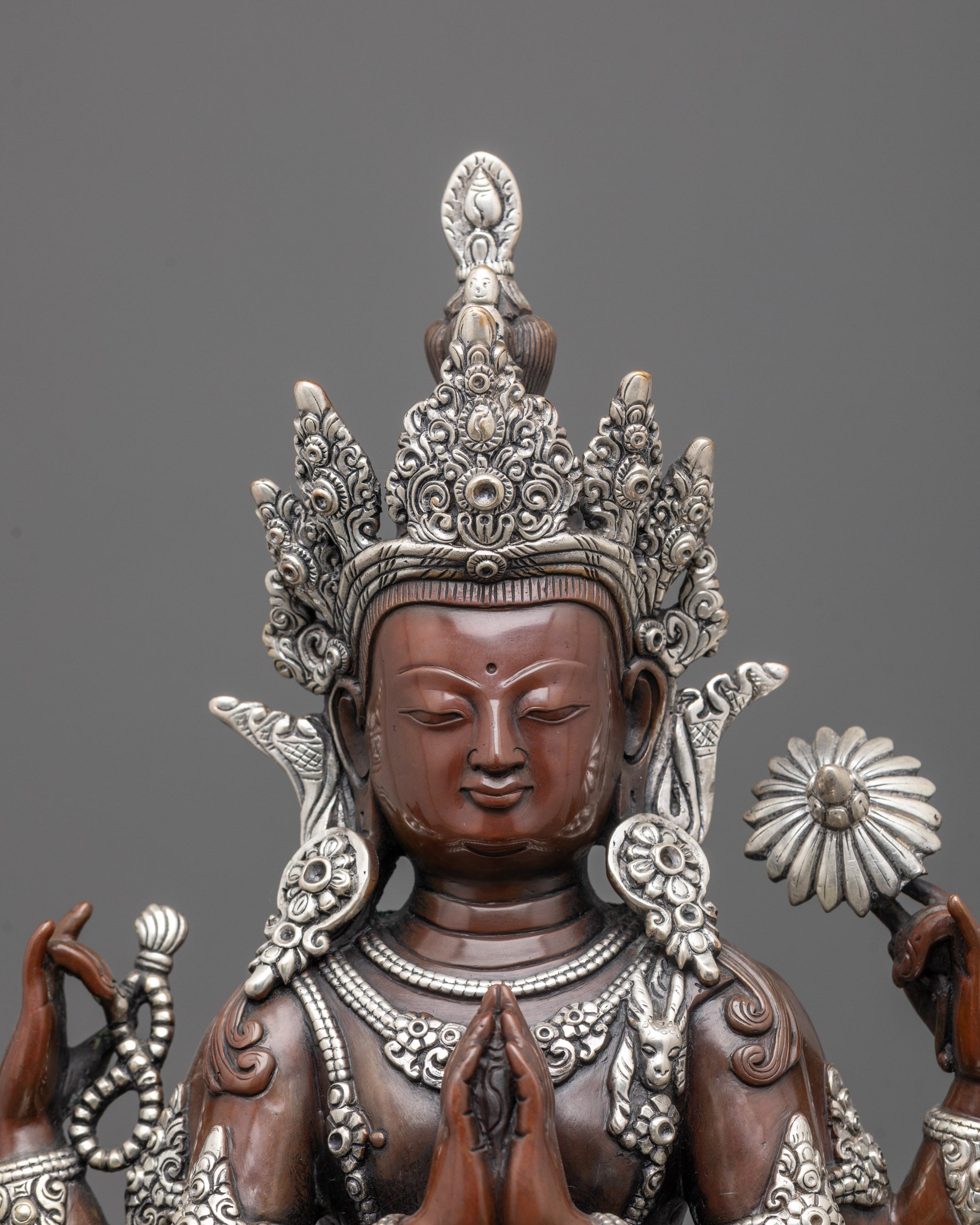 Close up of Chenrezig’s crown and jewelry with silver plating on oxidized copper texture