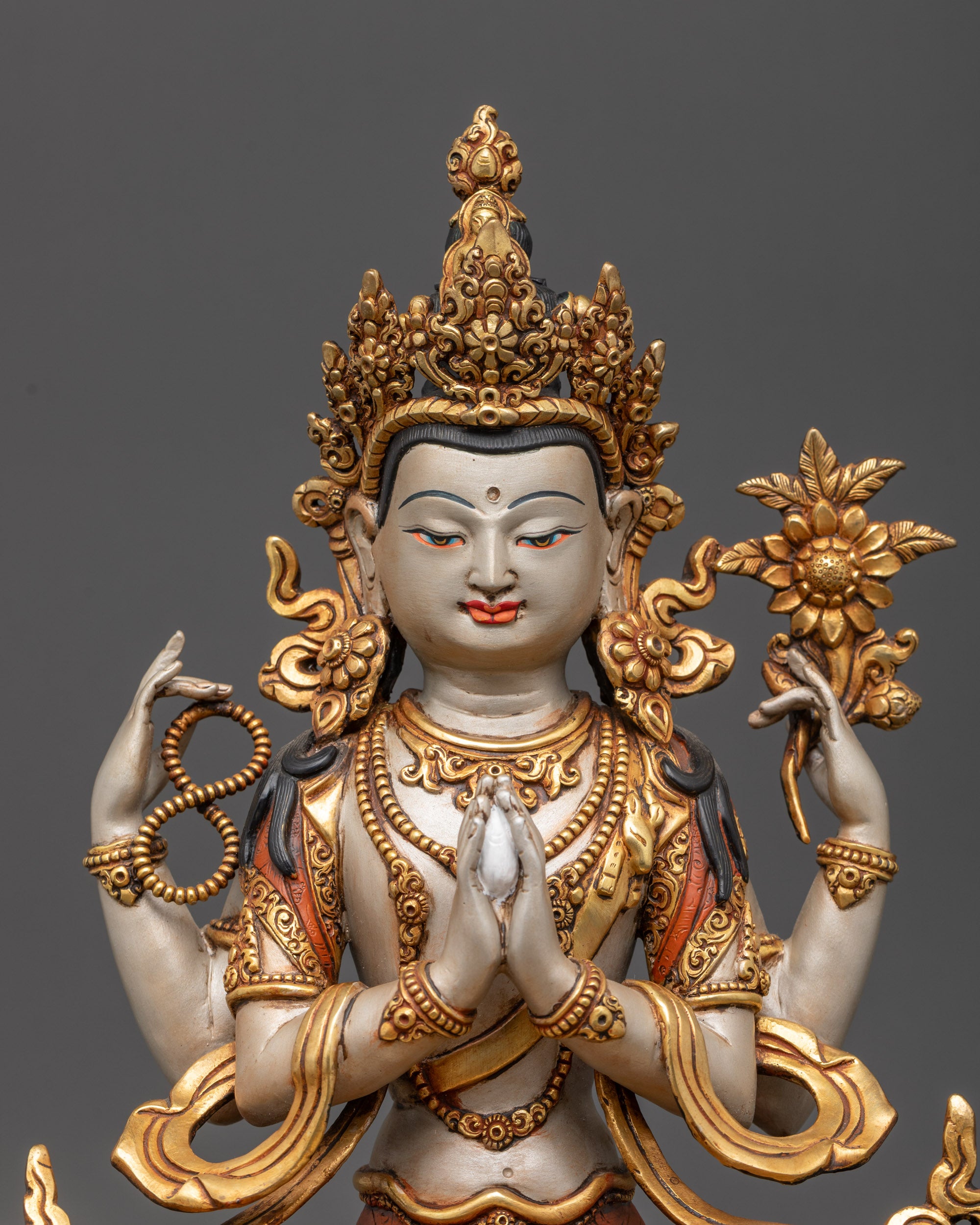 Close up of Chenrezig statue holding crystal rosary, lotus blossom, and wish-fulfilling gem