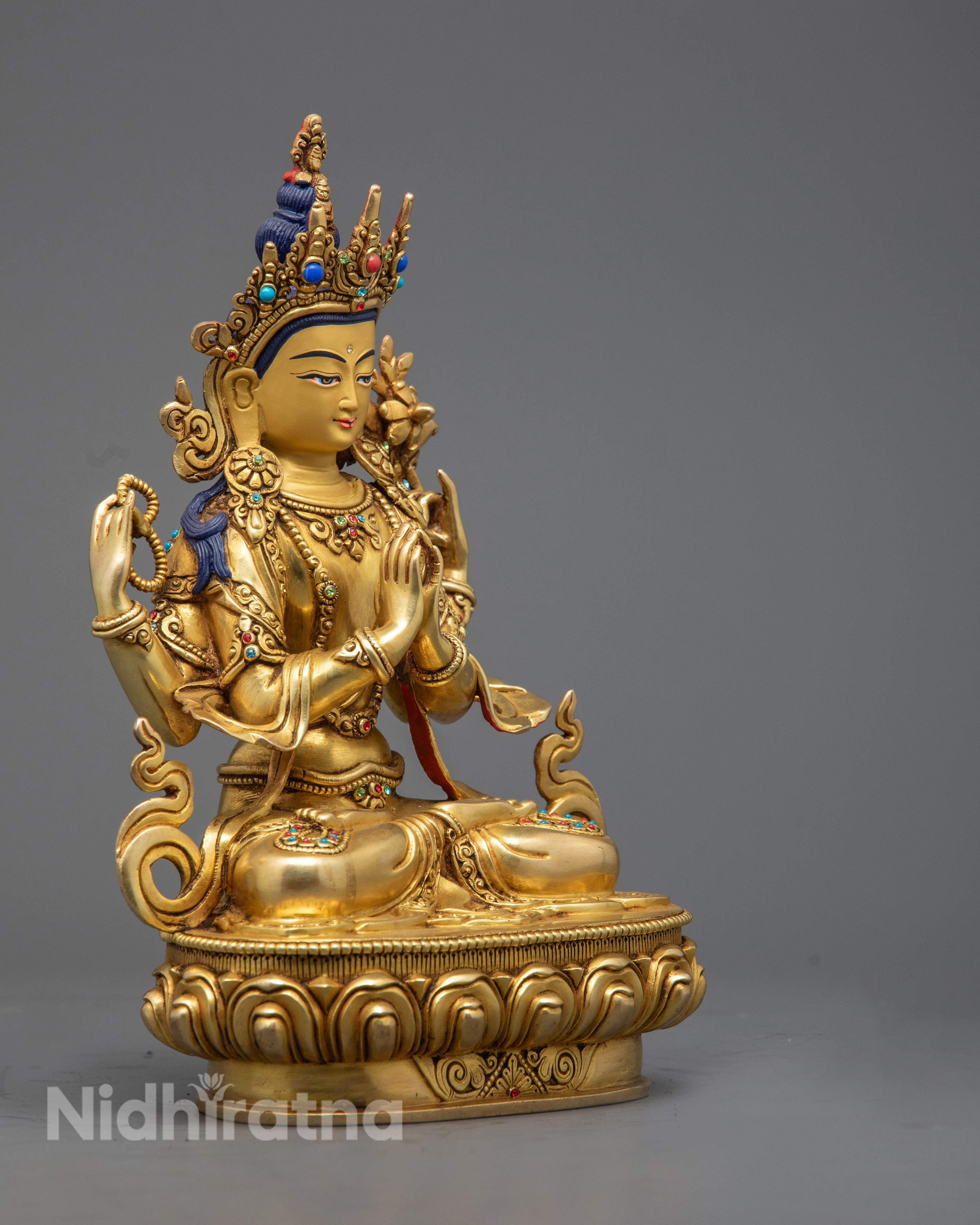 Close‑up of Chenrezig statue’s halo and varada mudra hand, highlighting intricate gold gilding and vibrant acrylic color details.