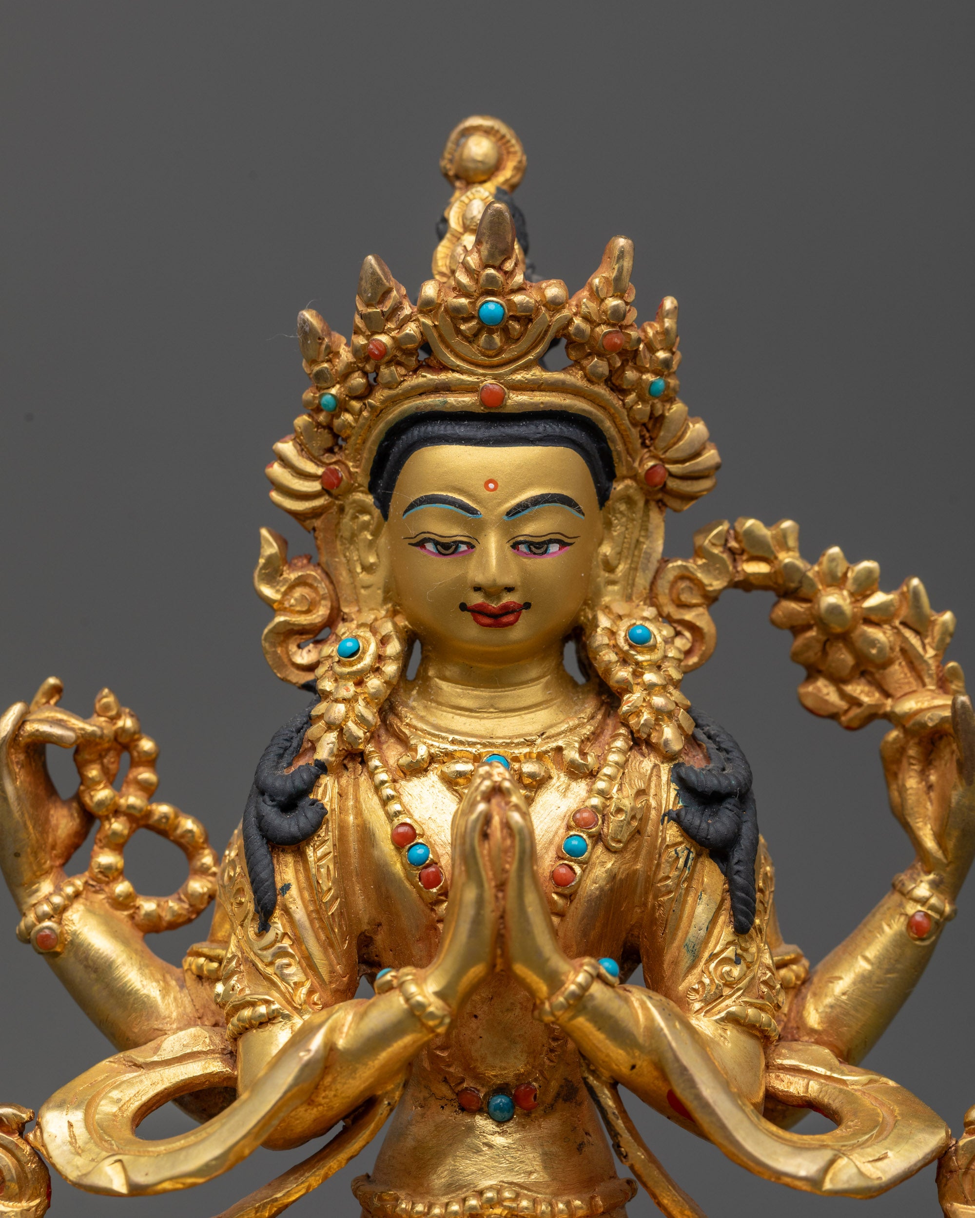 Close up of Chenrezig statue showing crown, jewelry, and serene facial expression
