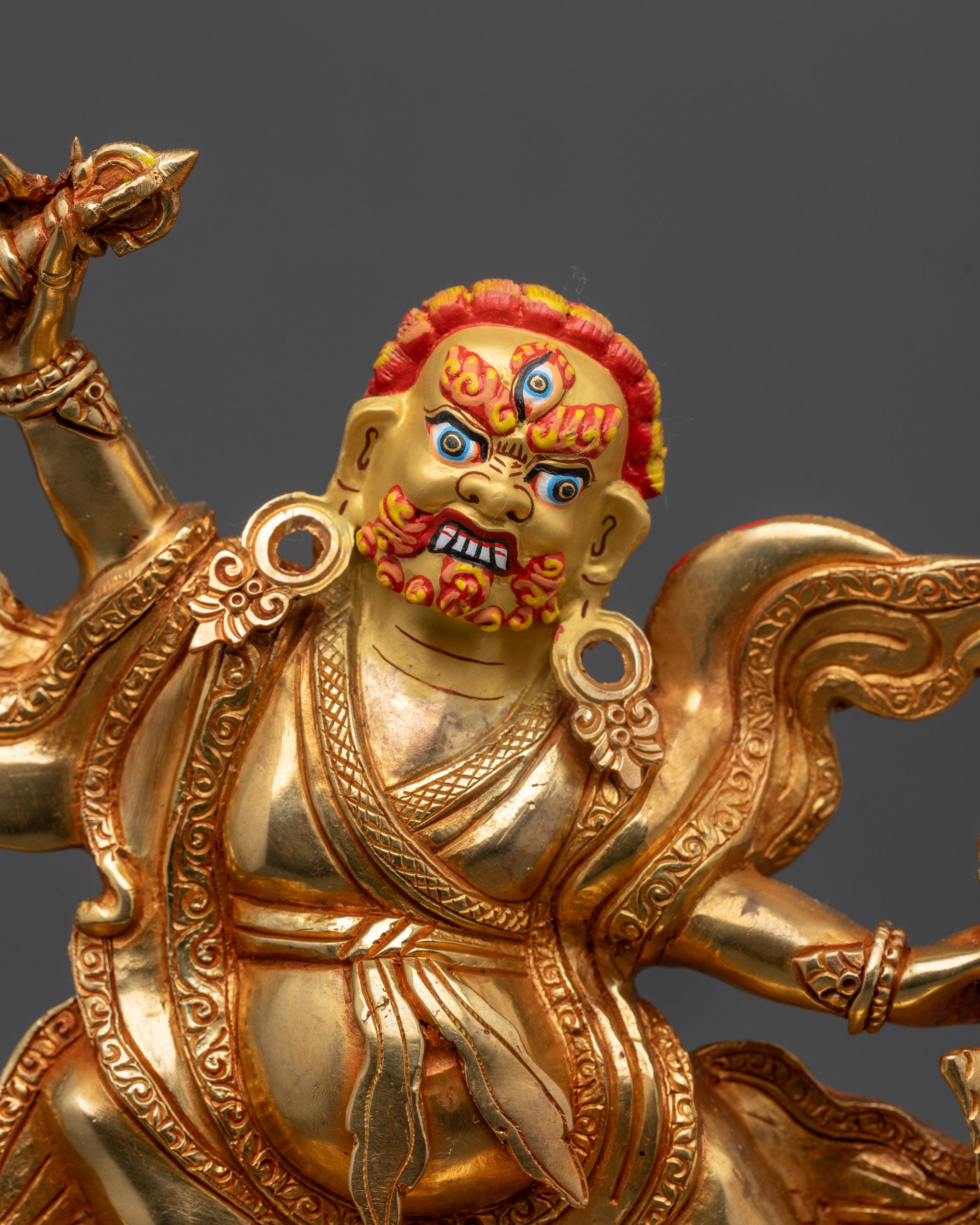 Close up of Dorje Drolo statue showing wrathful expression and third eye on gold-gilded face